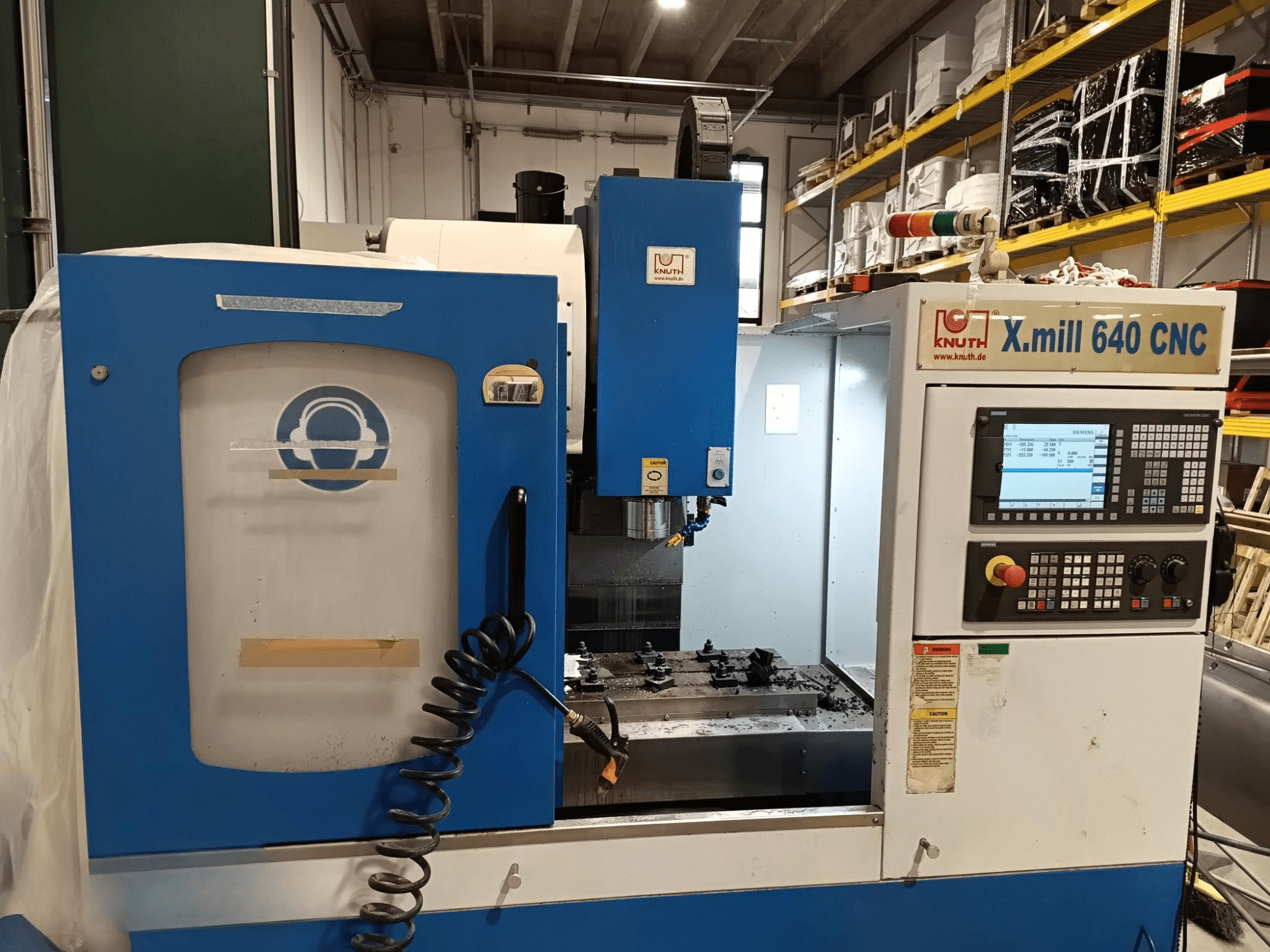 Máquina CNC Knuth X.mill 640 em vista lateral, com um painel de controlo, área do fuso e configuração visível da peça de trabalho.