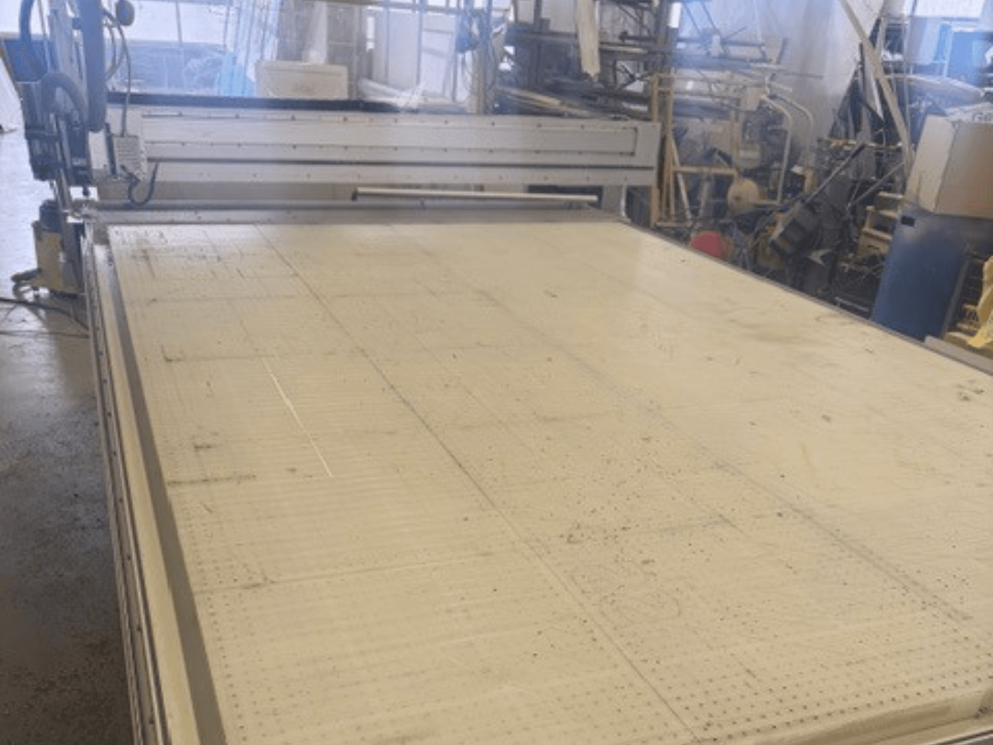 Máquina de corte de grandes dimensões com uma superfície plana, mostrando a estrutura e a calha de guia; vista de um ângulo numa oficina.