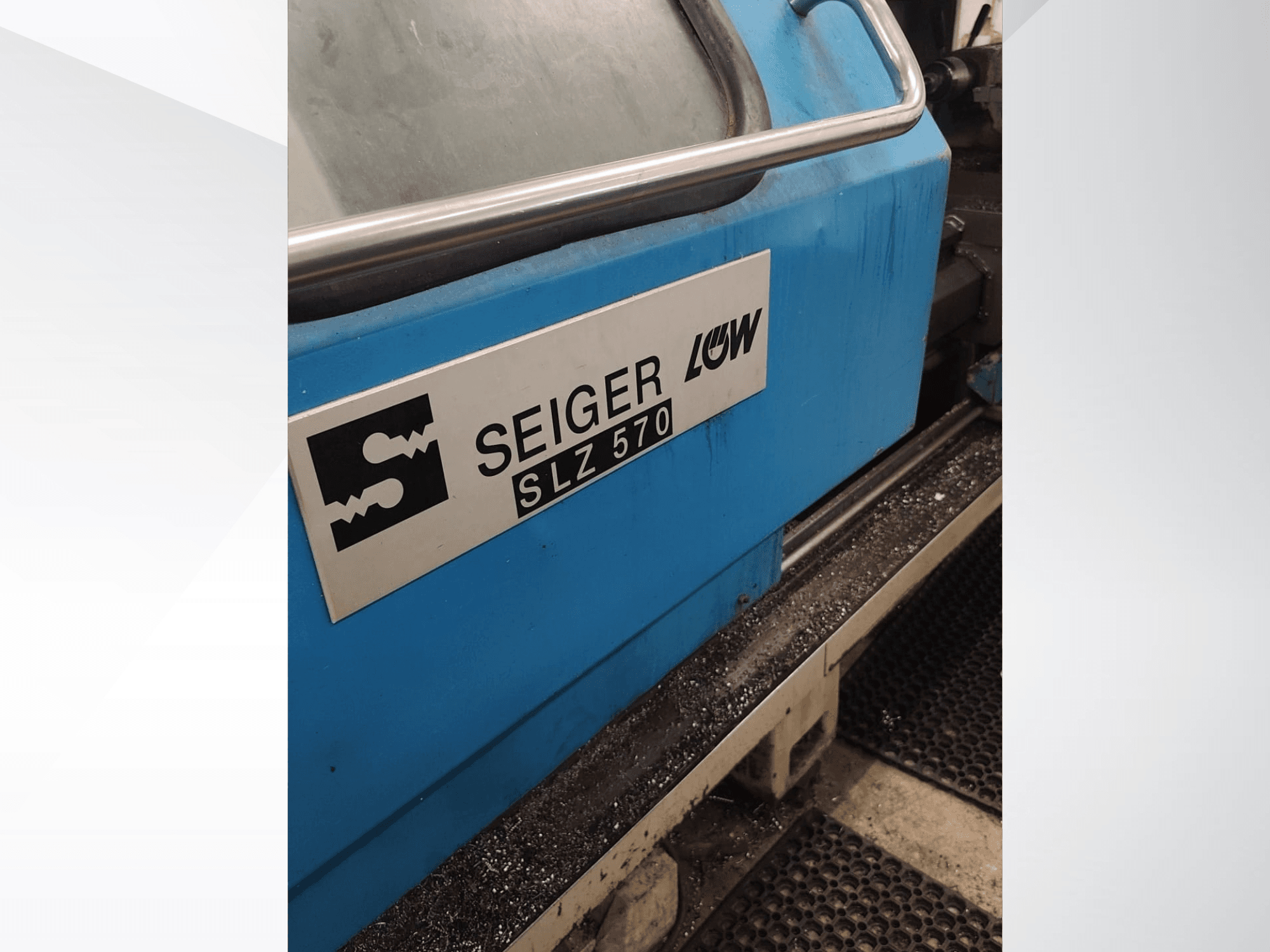 Vista lateral em grande plano da máquina de torneamento SEIGER SLZ570, com exterior azul e logótipo, apresentando as funcionalidades de controlo operacional.