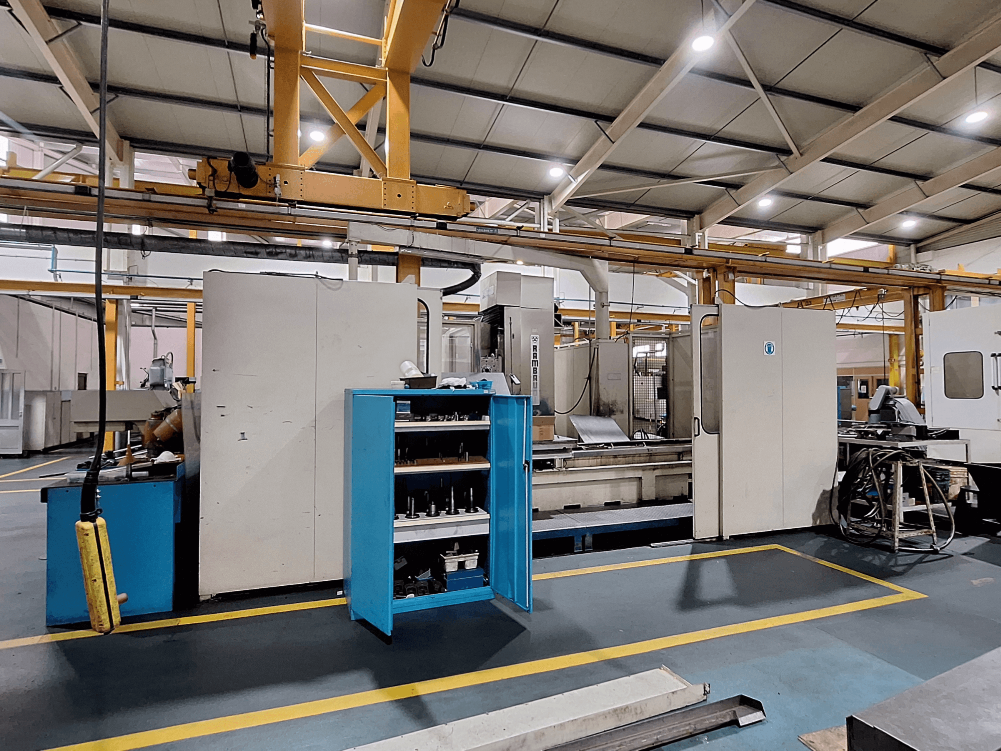 Fresadora de pórtico Rambaudi RX 1250, vista frontal com armazenamento de ferramentas, num espaço de trabalho industrial espaçoso.