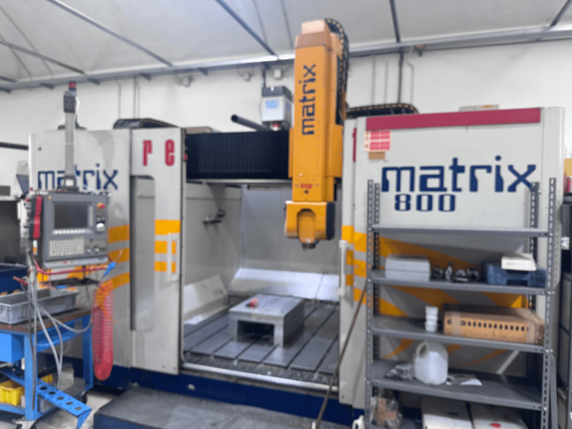 Máquina CNC Matrix 800 numa vista de oficina, com painel de controlo, ferramentas e mesa de trabalho com vários objectos.