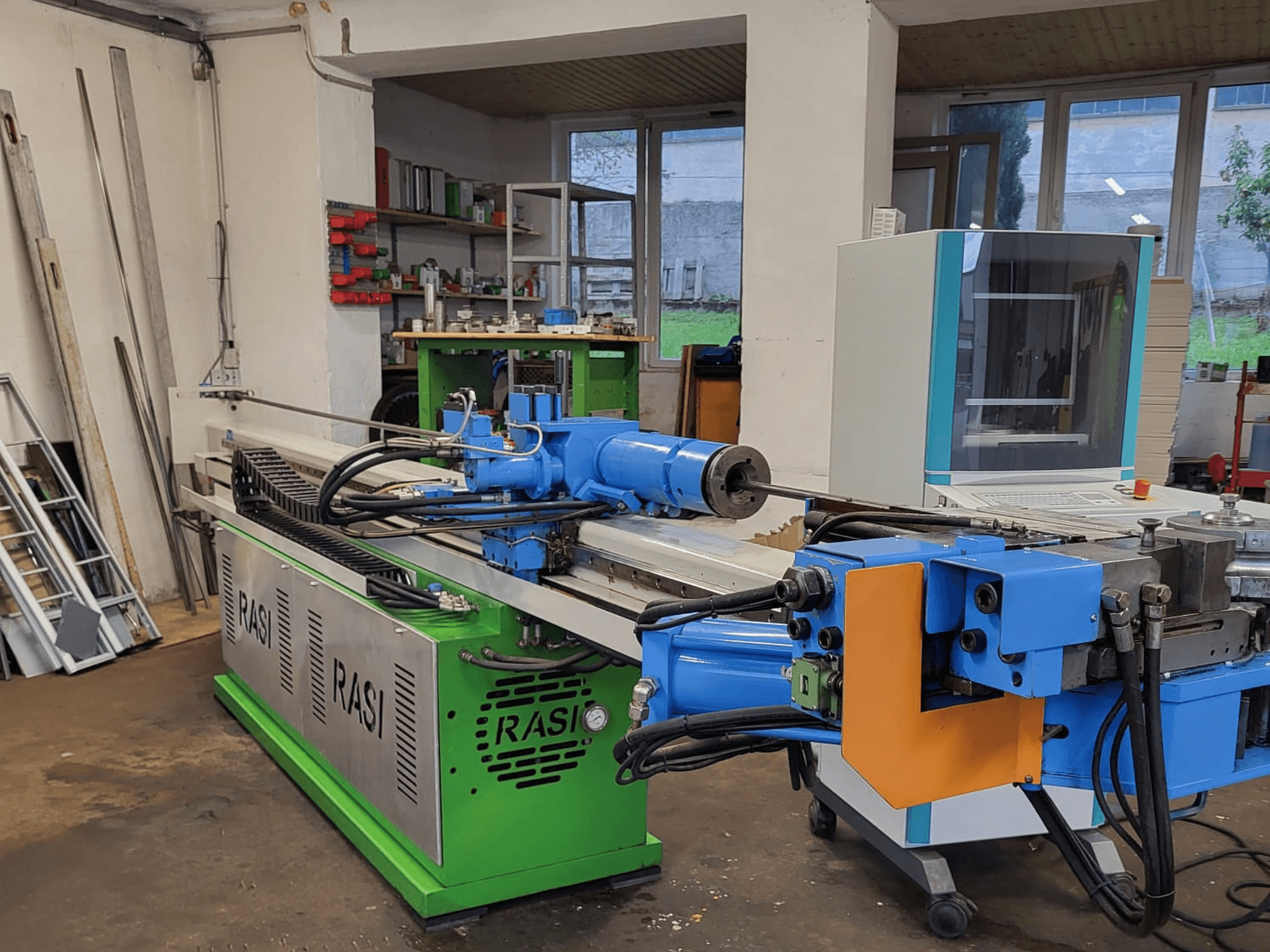 Máquina-ferramenta Rasi S 80.6 L G-V3C50 numa oficina, vista lateral mostrando componentes azuis e verdes e painel de controlo.