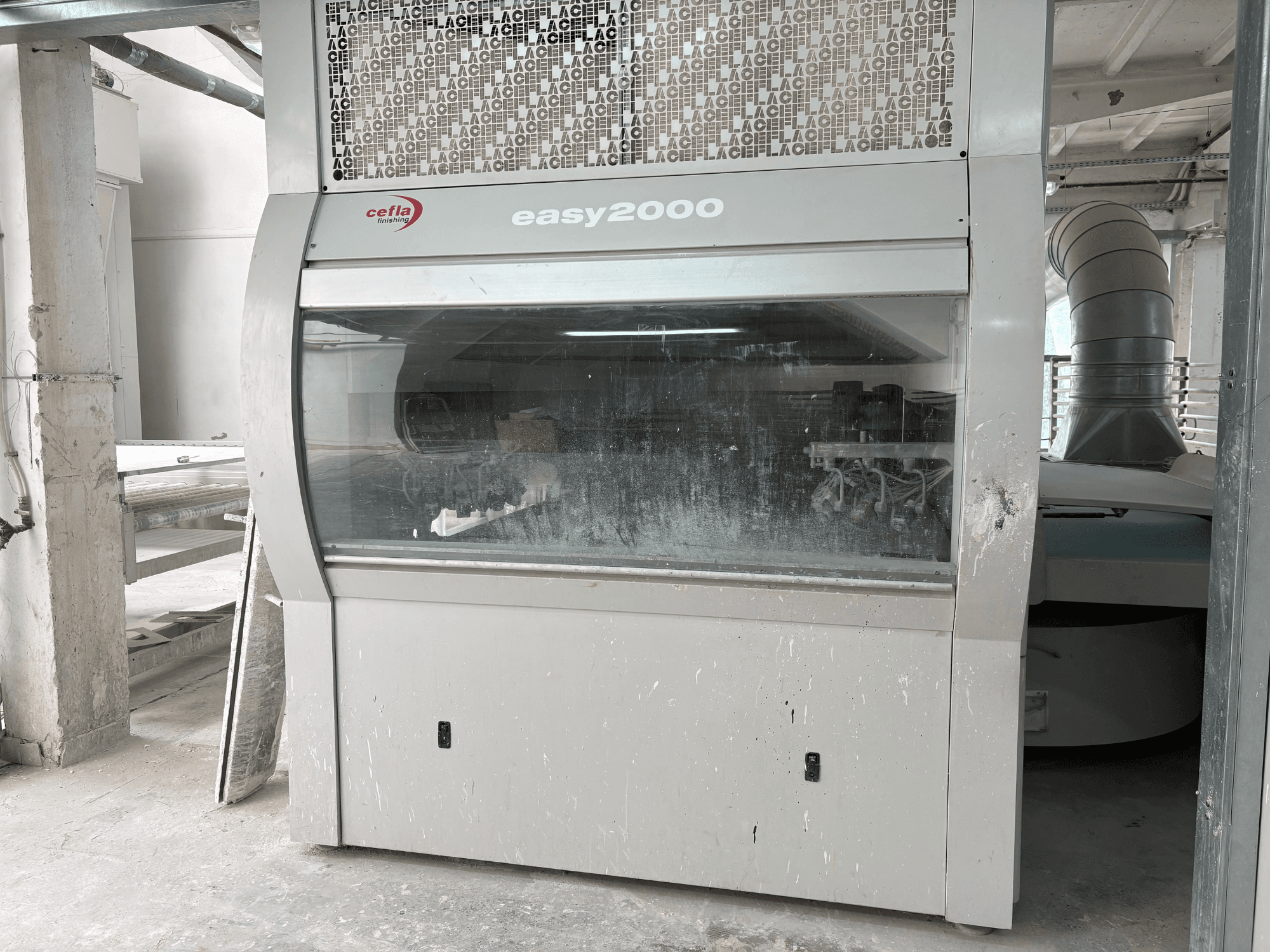 Máquina Cefla EASY 2000 D vista de frente, com um grande painel transparente, superfície empoeirada e componentes internos visíveis.