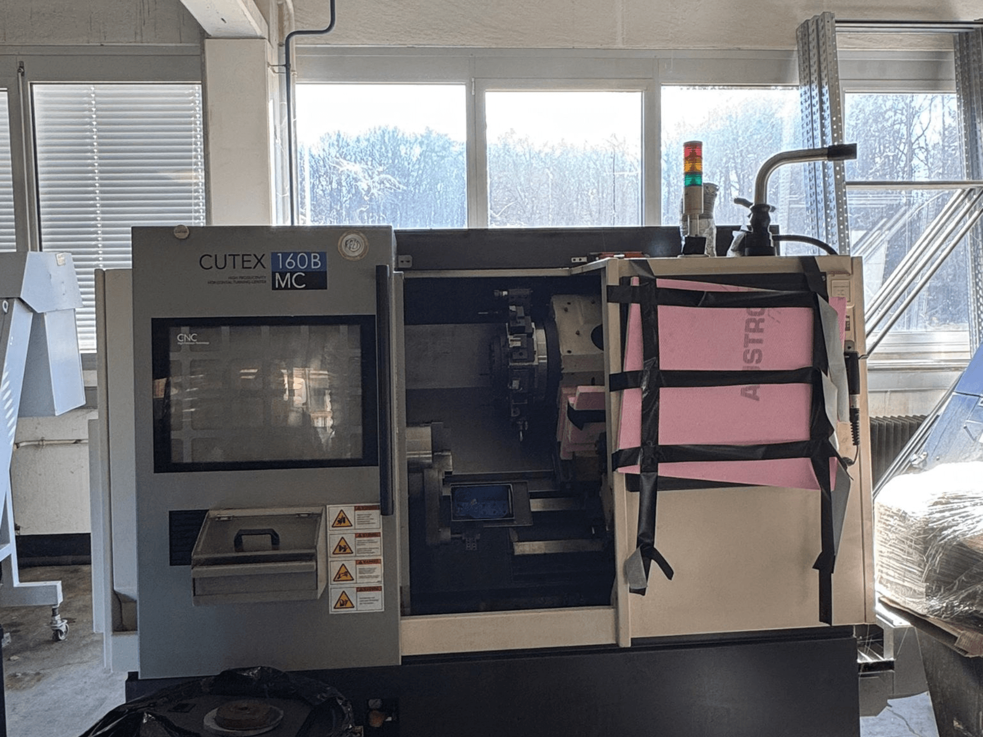 Vista frontal do torno horizontal HWACHEON CUTEX 160 B VDI, com painel de controlo e depósito de líquido de arrefecimento, equipado com uma luz de segurança.