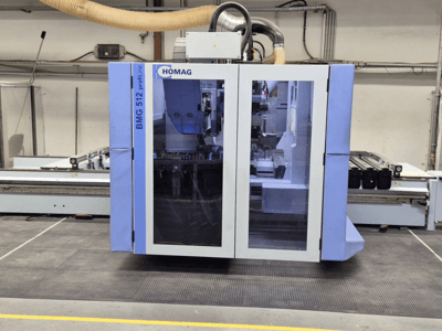 Máquina CNC HOMAG BMG 512 ProfiLine, vista frontal, com painel de vidro, ferramentas de precisão visíveis e ambiente industrial.