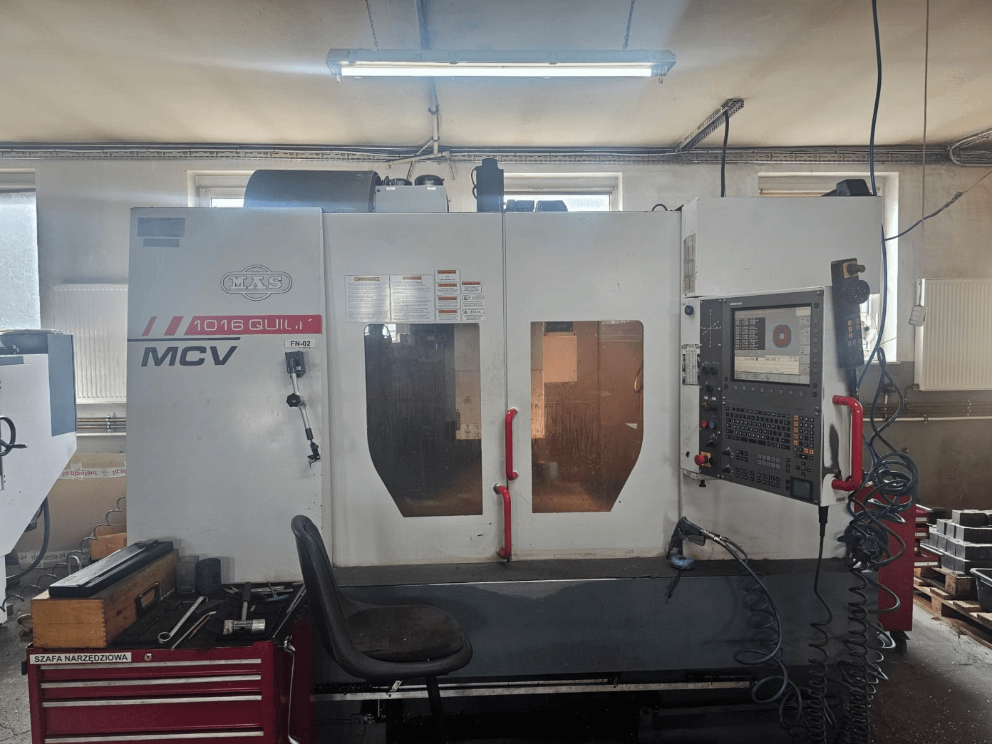 Máquina CNC MVS MCV 1016 QUILL, vista frontal, com painel de controlo, gaveta de ferramentas e espaço de trabalho com ferramentas.