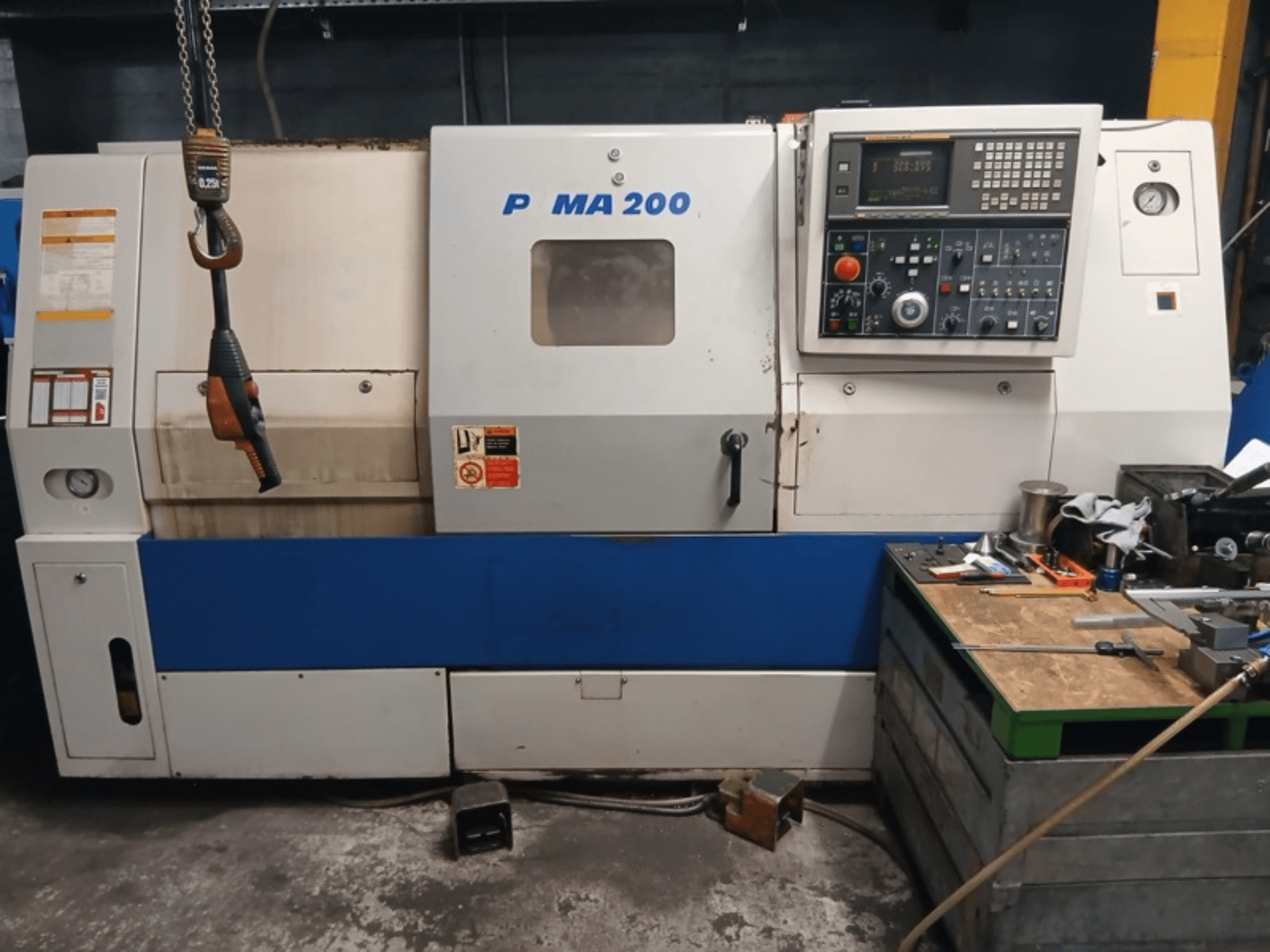 Vista frontal do torno horizontal DAEWOO EcoTurn 200, com o painel de controlo e as etiquetas de segurança.