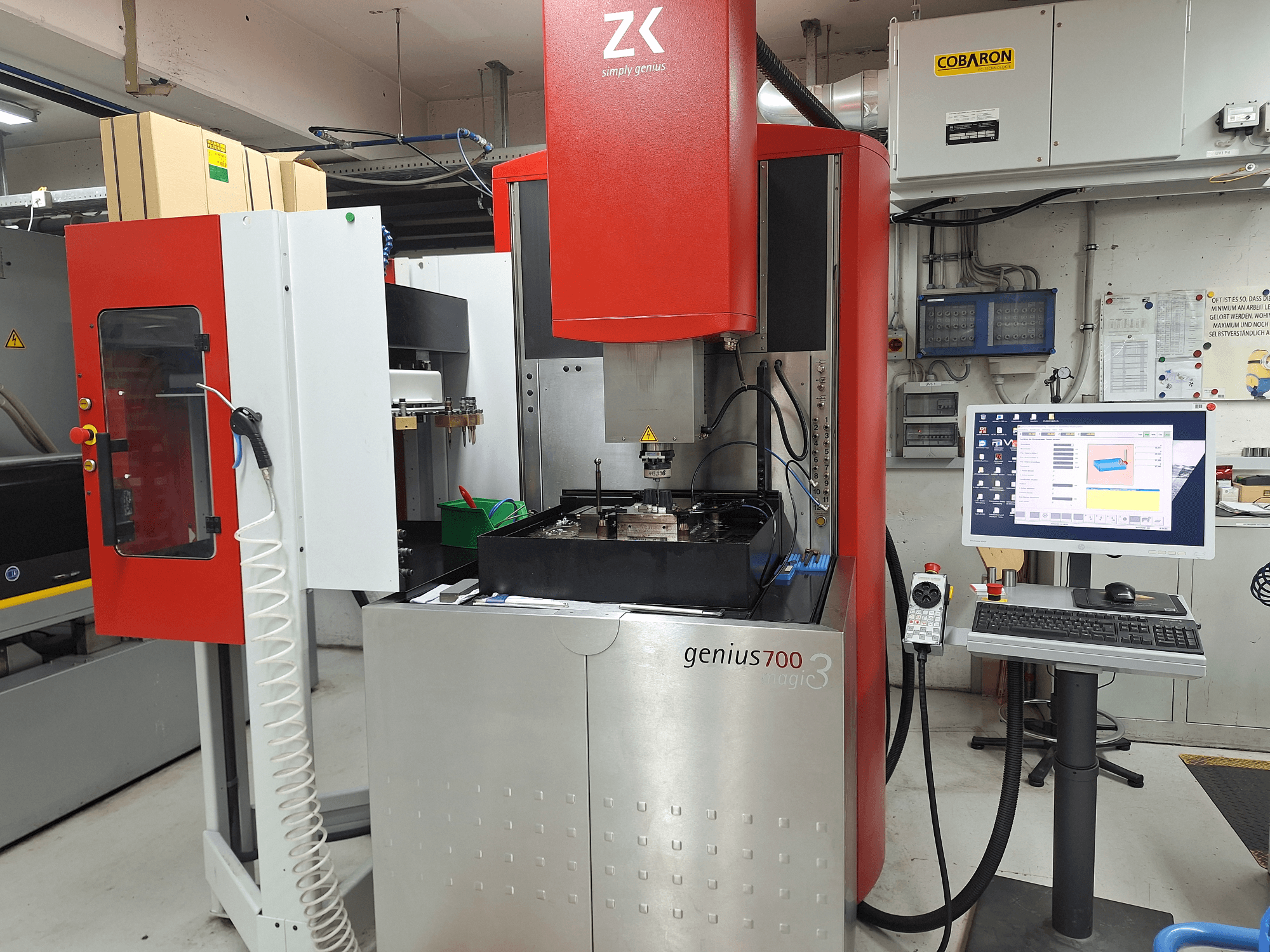 Fresadora Genius 700 da ZK, vista frontal, com painel de controlo com ecrã tátil e área de maquinação com ferramentas e materiais.
