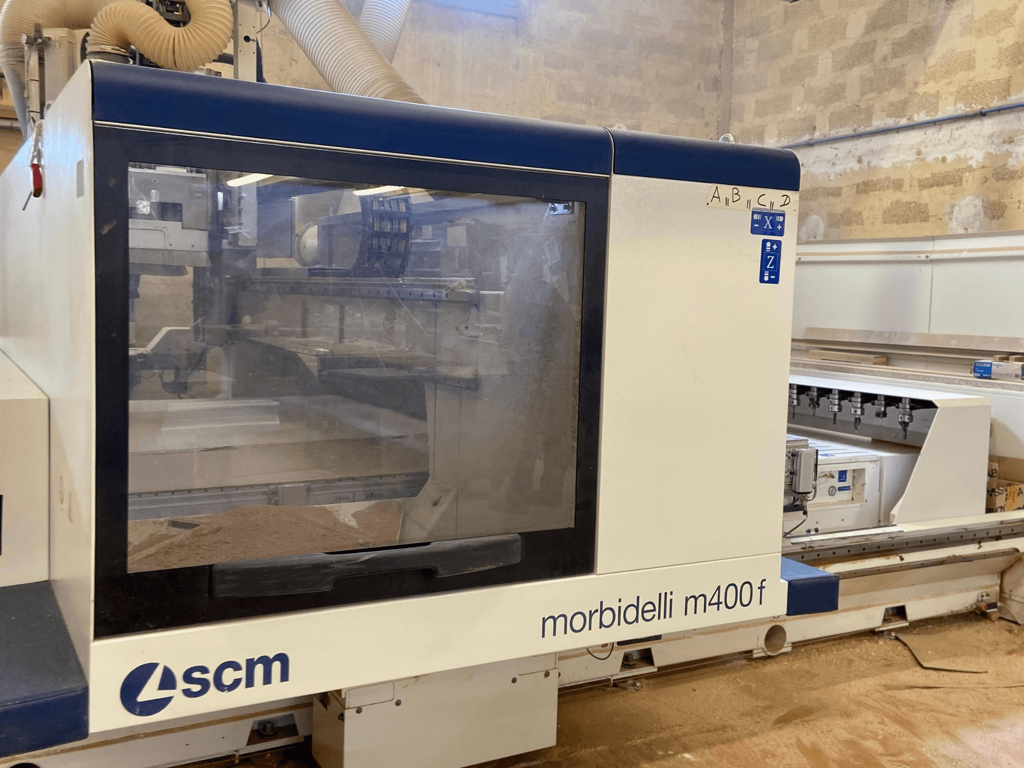Máquina CNC SCM Morbidelli M400F, vista frontal, com um painel de controlo e serradura visível no chão.