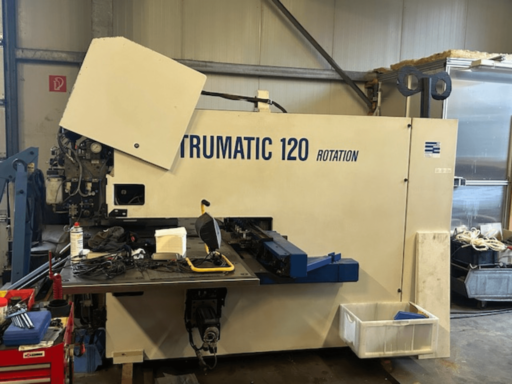 Puncionadora CNC TRUMPF Trumatic 120R numa oficina, vista frontal mostrando o painel de controlo e as ferramentas na mesa.