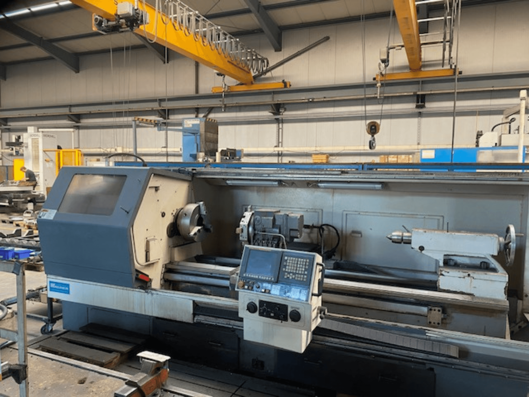 Máquina de torno de precisão Wabeco, vista frontal com painel de controlo, mostrando as configurações do fuso e das ferramentas num ambiente de fábrica.