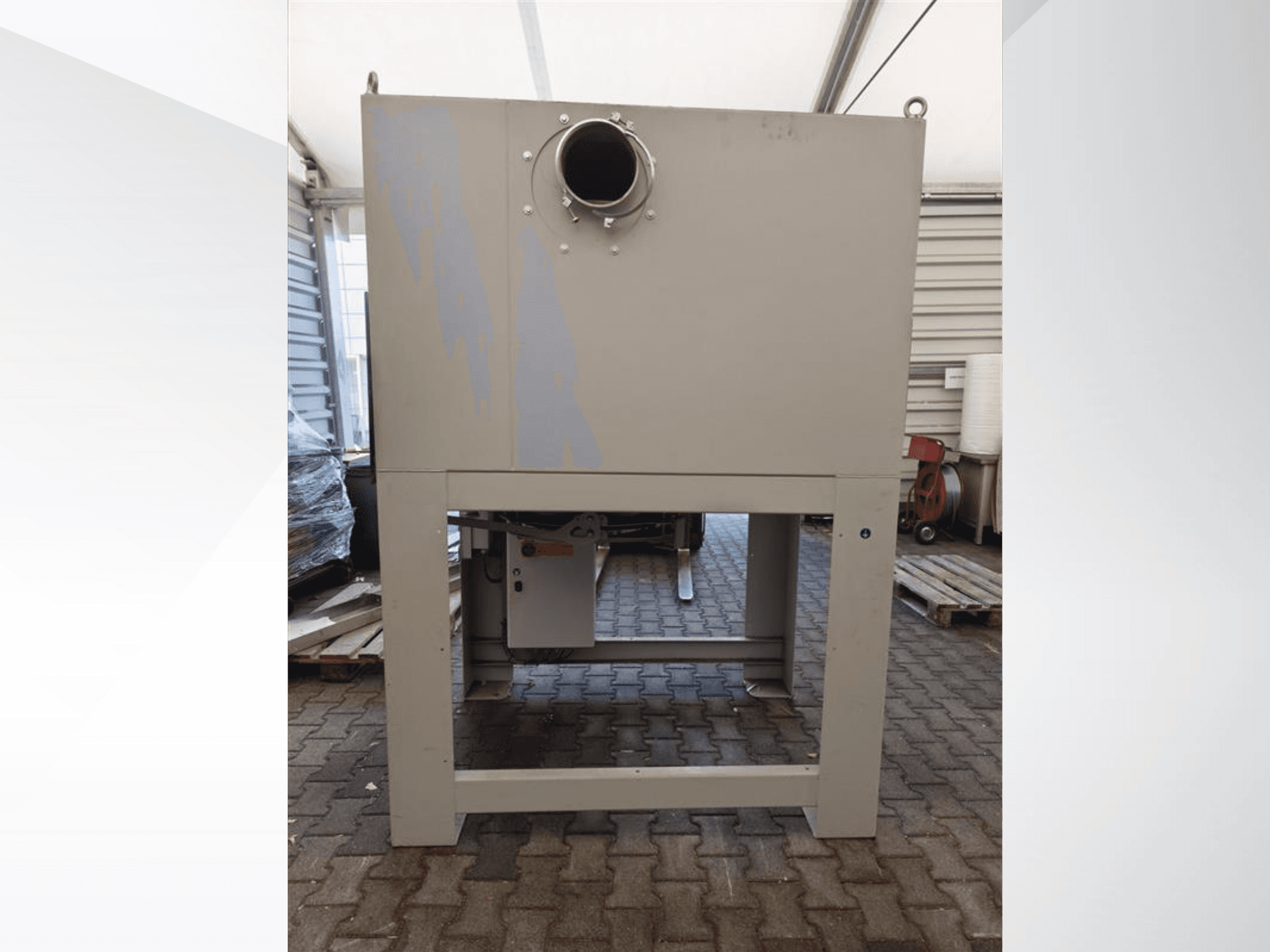 Coletor de pó industrial cinzento visto de frente, com uma grande abertura redonda e montado numa base robusta.