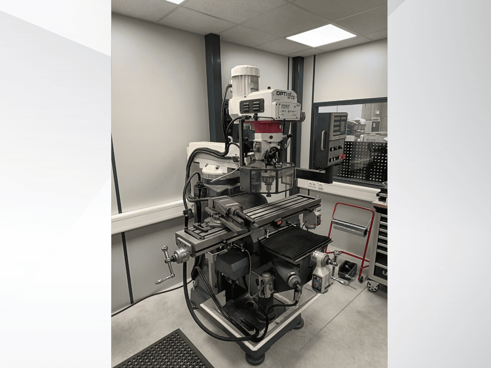 Centro de maquinagem vertical Optimum MF 4-B, visto de lado, apresentando uma mesa de trabalho detalhada, um painel de controlo e um motor.