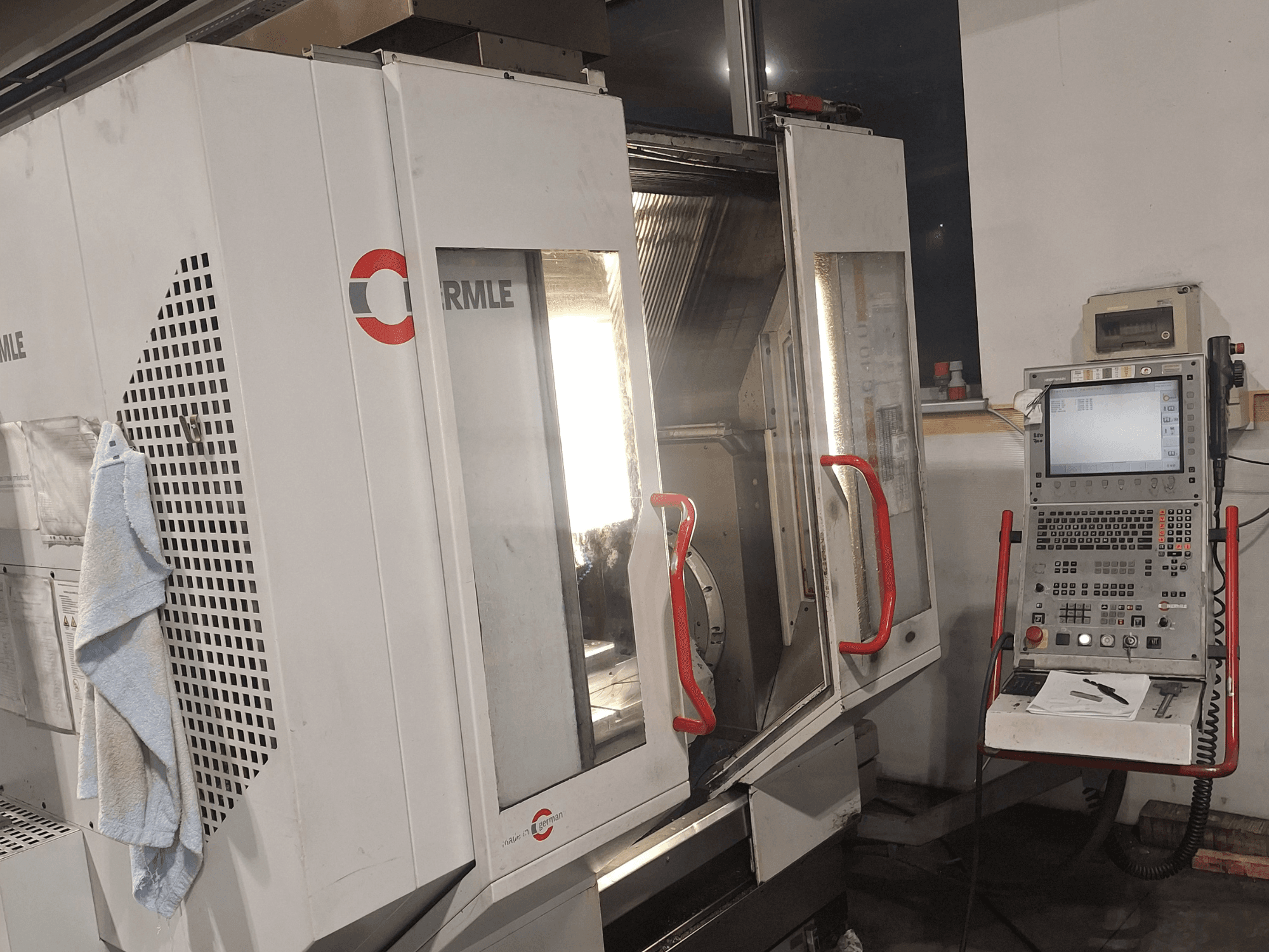 Máquina CNC da marca Cormile, vista frontal mostrando portas parcialmente abertas e painel de controlo com ecrã e botões.