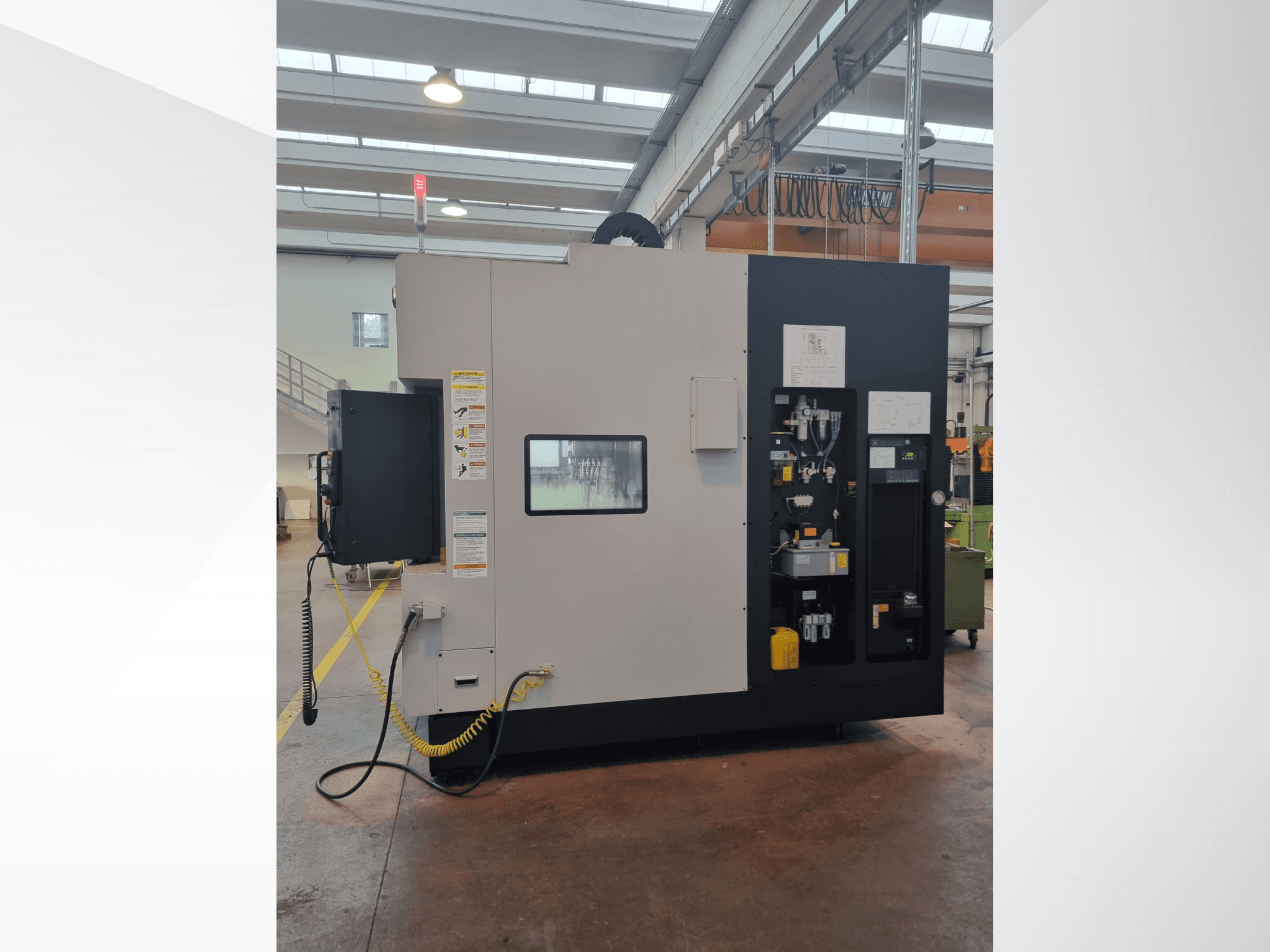 Máquina industrial vista de lado, apresenta um painel de controlo com botões, indicadores e uma etiqueta de aviso de segurança.