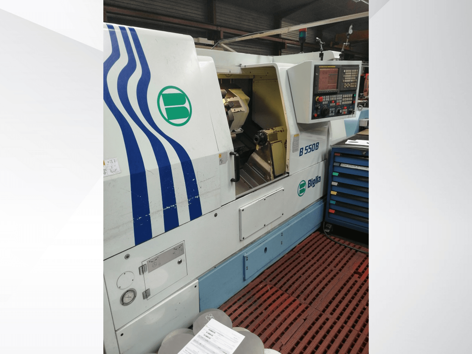 Torno CNC Biglia B 550 B mostrado de frente, com painel de controlo, área de trabalho em metal e armazenamento de ferramentas coloridas.