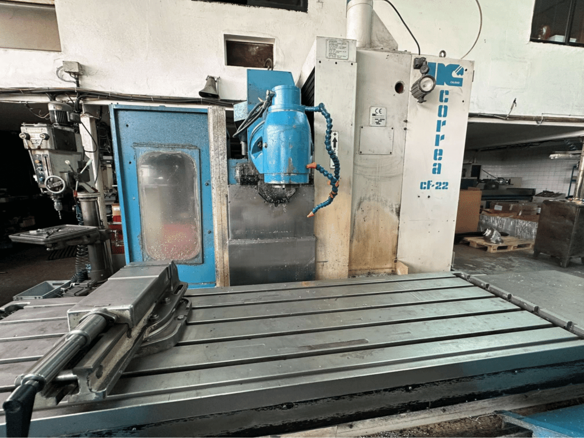 Fresadora Correa CF-22, vista frontal; possui uma mesa de trabalho metálica e um painel de controlo azul e branco com botões.