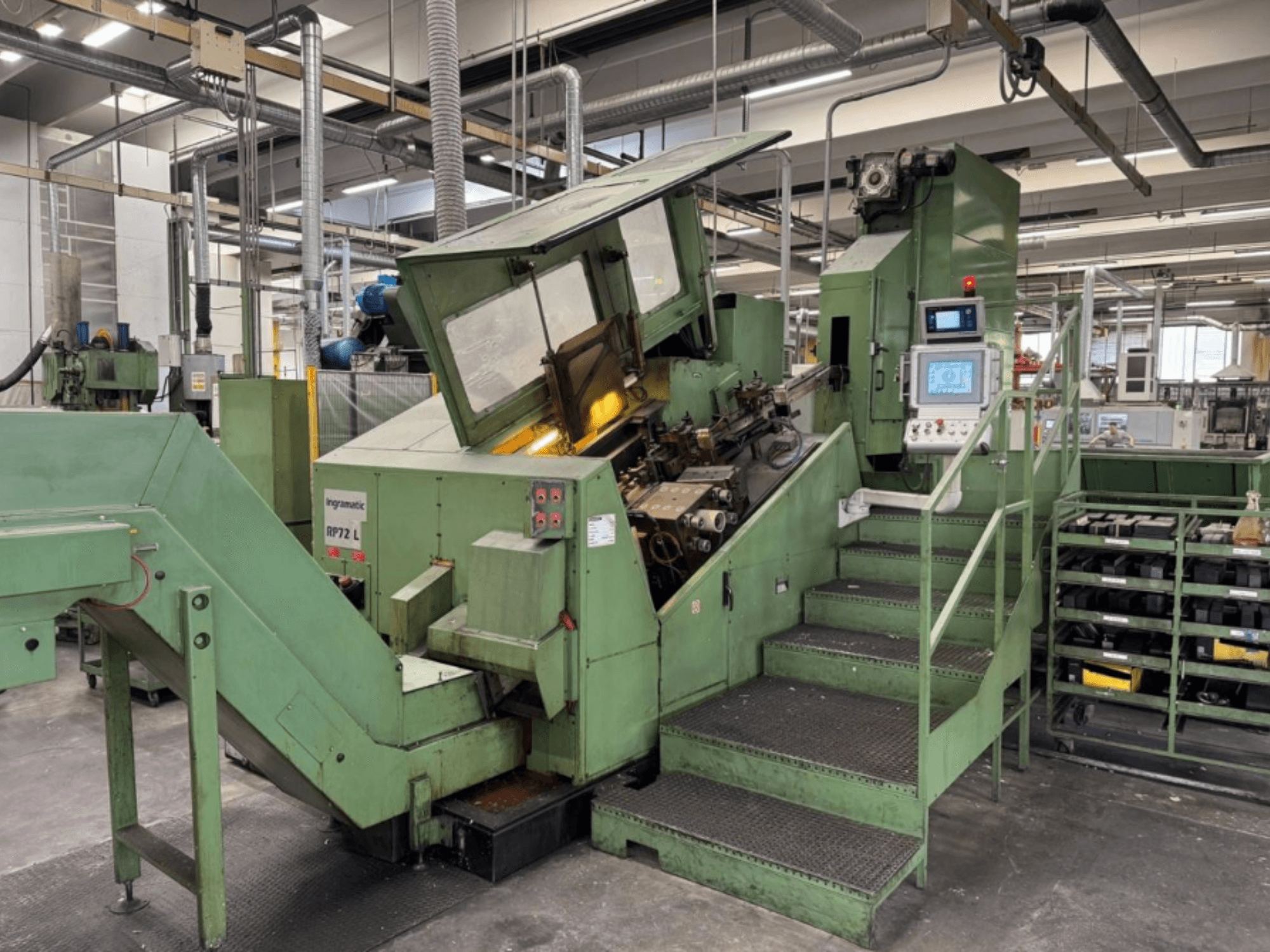 Ingramatic RP72 L, máquina industrial em verde, vista frontal; possui um painel de controlo e degraus com uma plataforma de grelha metálica.