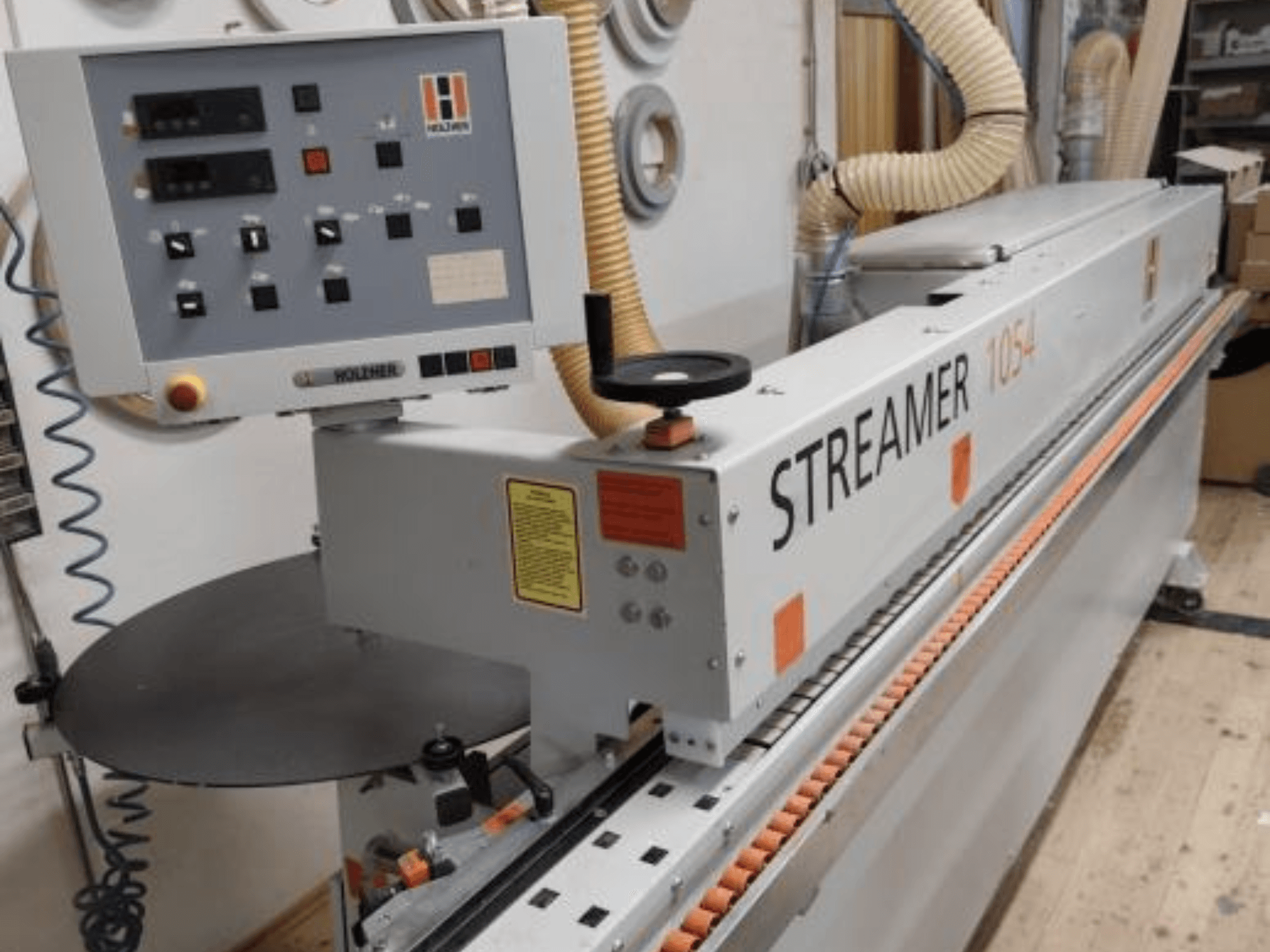 Coladeira de bordos HOLZHER Streamer 1054, vista lateral mostrando o painel de controlo e o sistema de alimentação sobre um fundo de oficina.