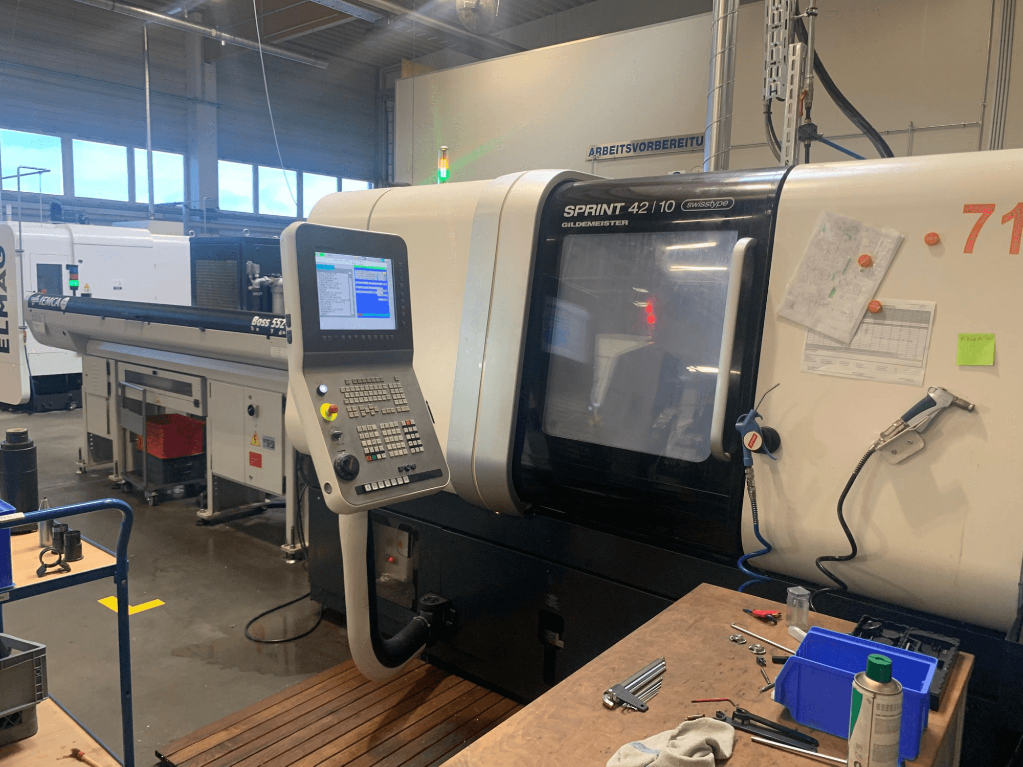 DMG MORI Sprint 42/10 linear Swiss Type Turning Machine, vista frontal, com um painel de controlo e espaço de trabalho desordenado.