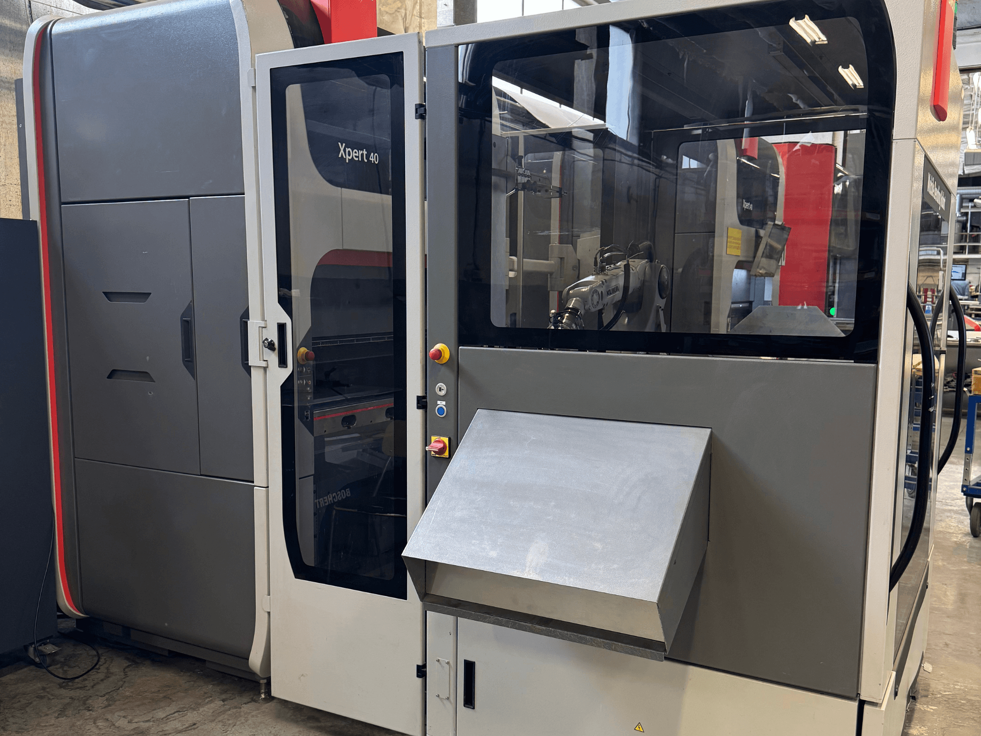 A prensa dobradeira Bystronic Xpert 40/1030 em vista frontal, mostrando o painel de comando, a caixa de vidro e as caraterísticas de design limpo.