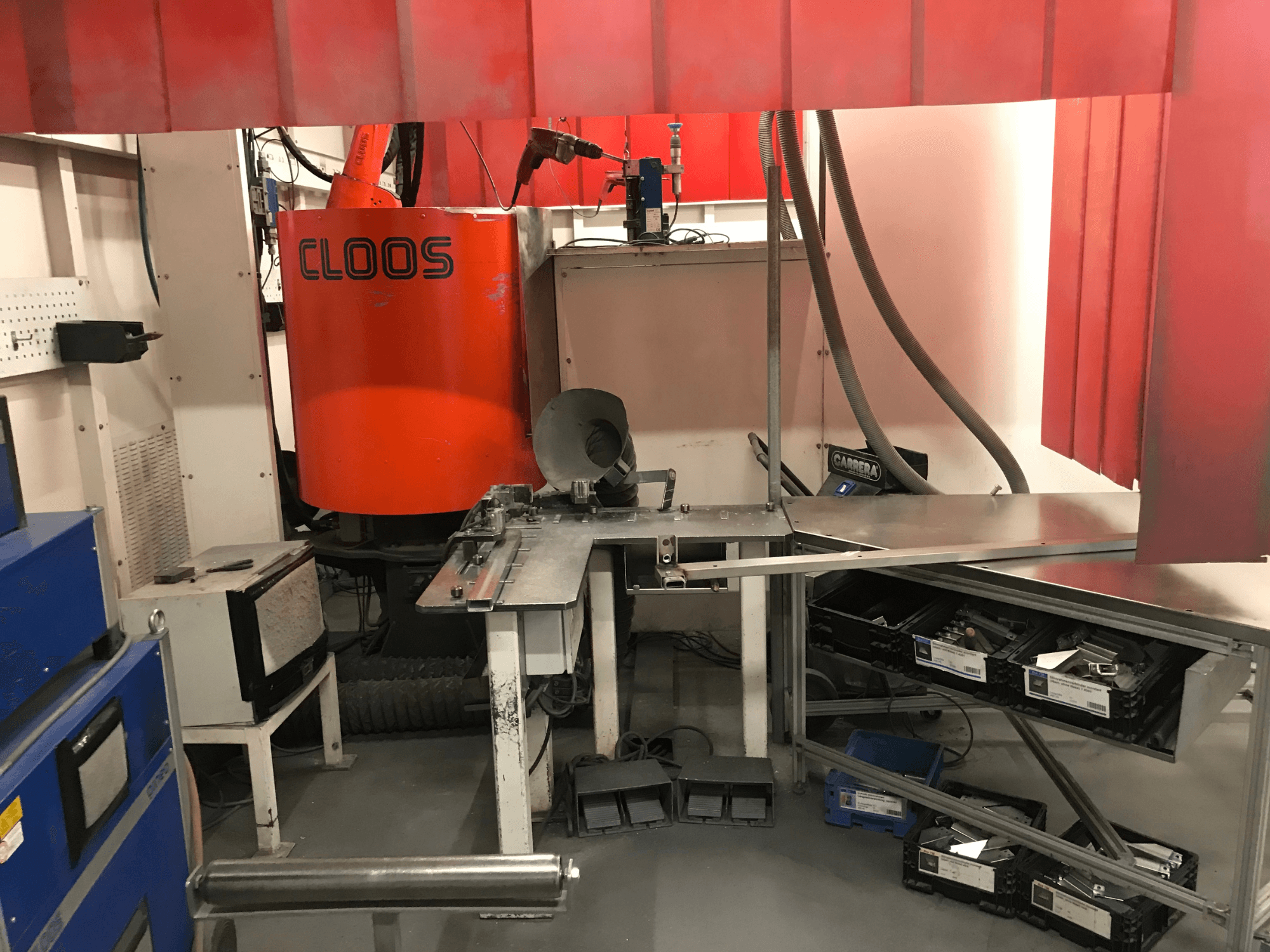 Sistema para oficina de soldadura da DESSAUER, vista frontal que mostra o braço robótico, a bancada de metalurgia e as áreas de armazenamento num ambiente de oficina.