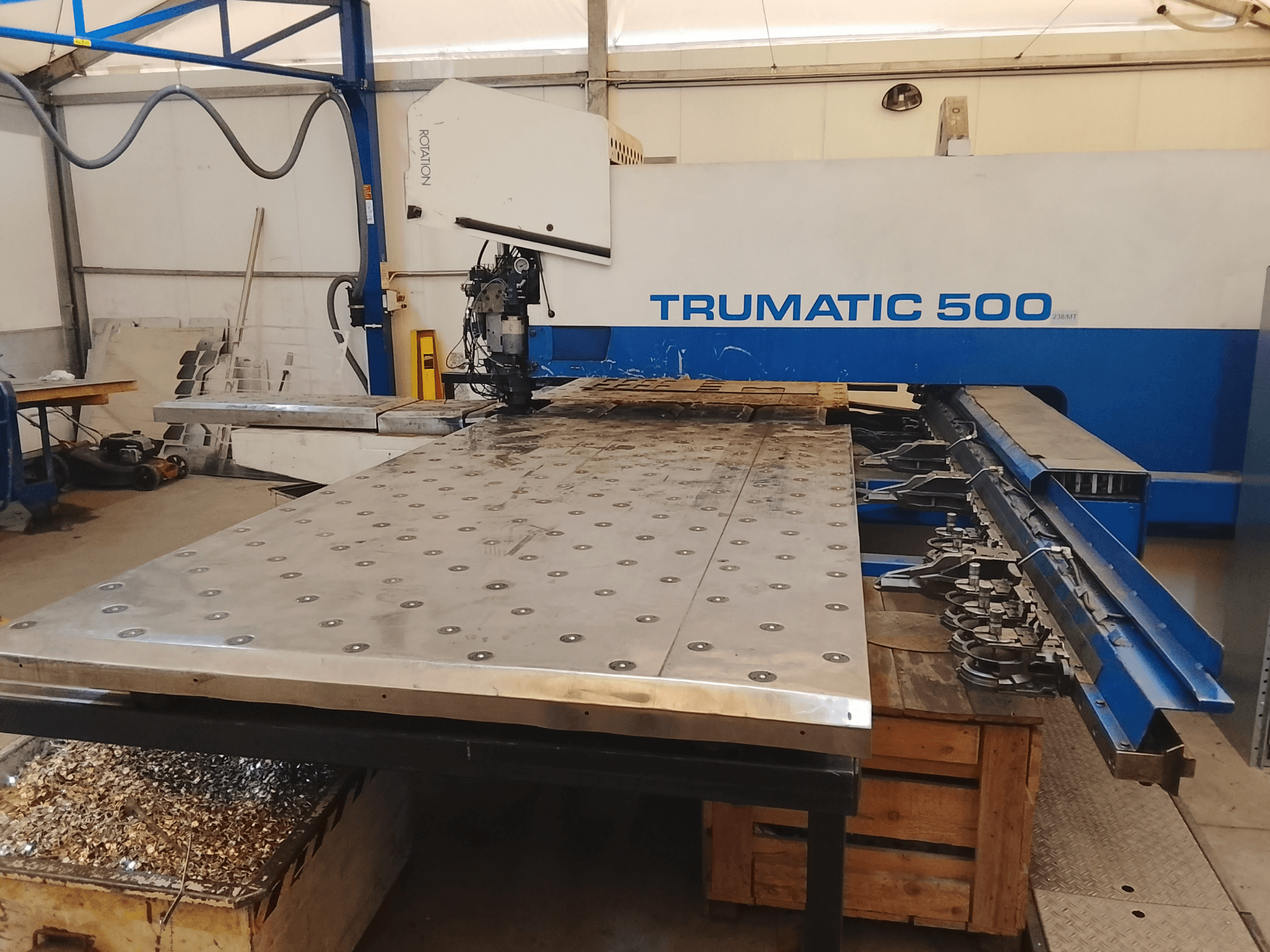 Máquina CNC Trumatic 500, vista de cima, com uma grande mesa de corte de metal com ferramentas montadas e aparas por baixo.