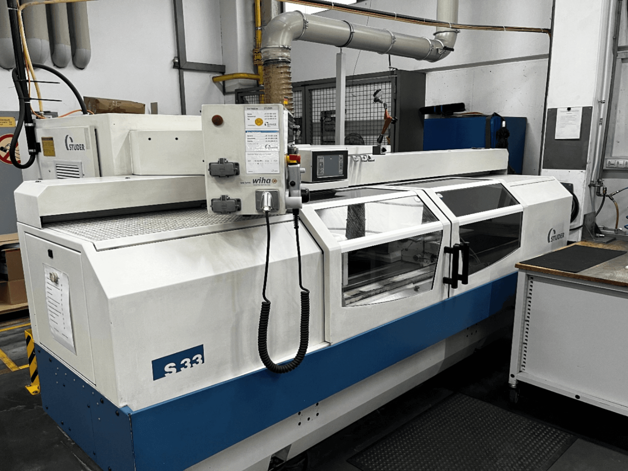 STUDER S33 Máquina de retificação cilíndrica CNC, vista frontal; possui painel de controlo e portas de segurança em vidro. Ambiente industrial.