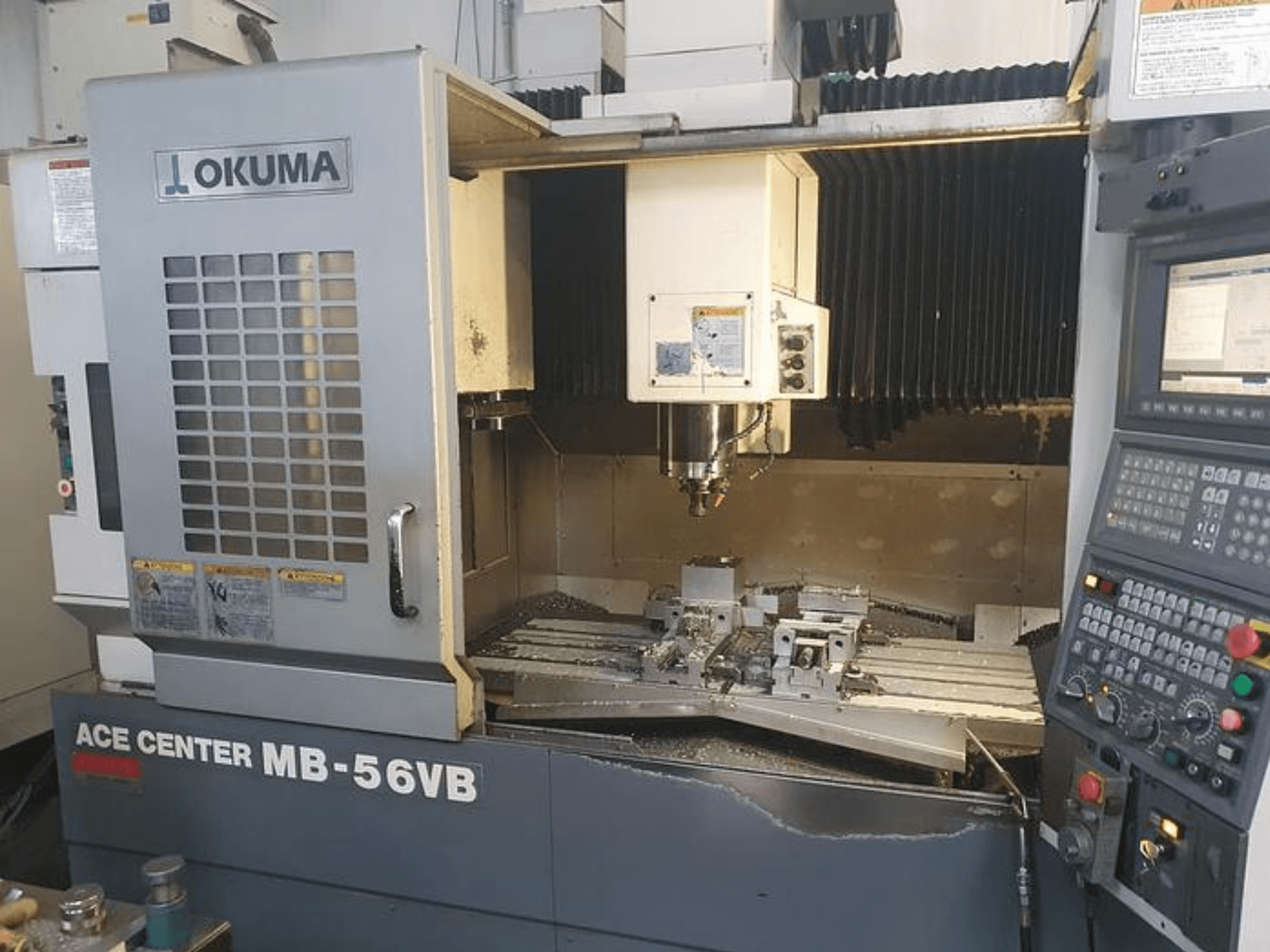 Fresadora CNC Okuma ACE CENTER MB-56VB em vista frontal, mostrando o painel de controlo e a área de maquinação.