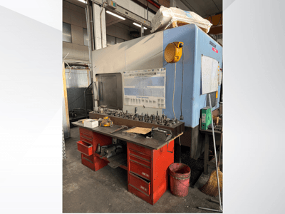 Centro de maquinagem Doosan com uma bancada de trabalho e arrumação vermelha, com ferramentas e equipamento, visto de frente.