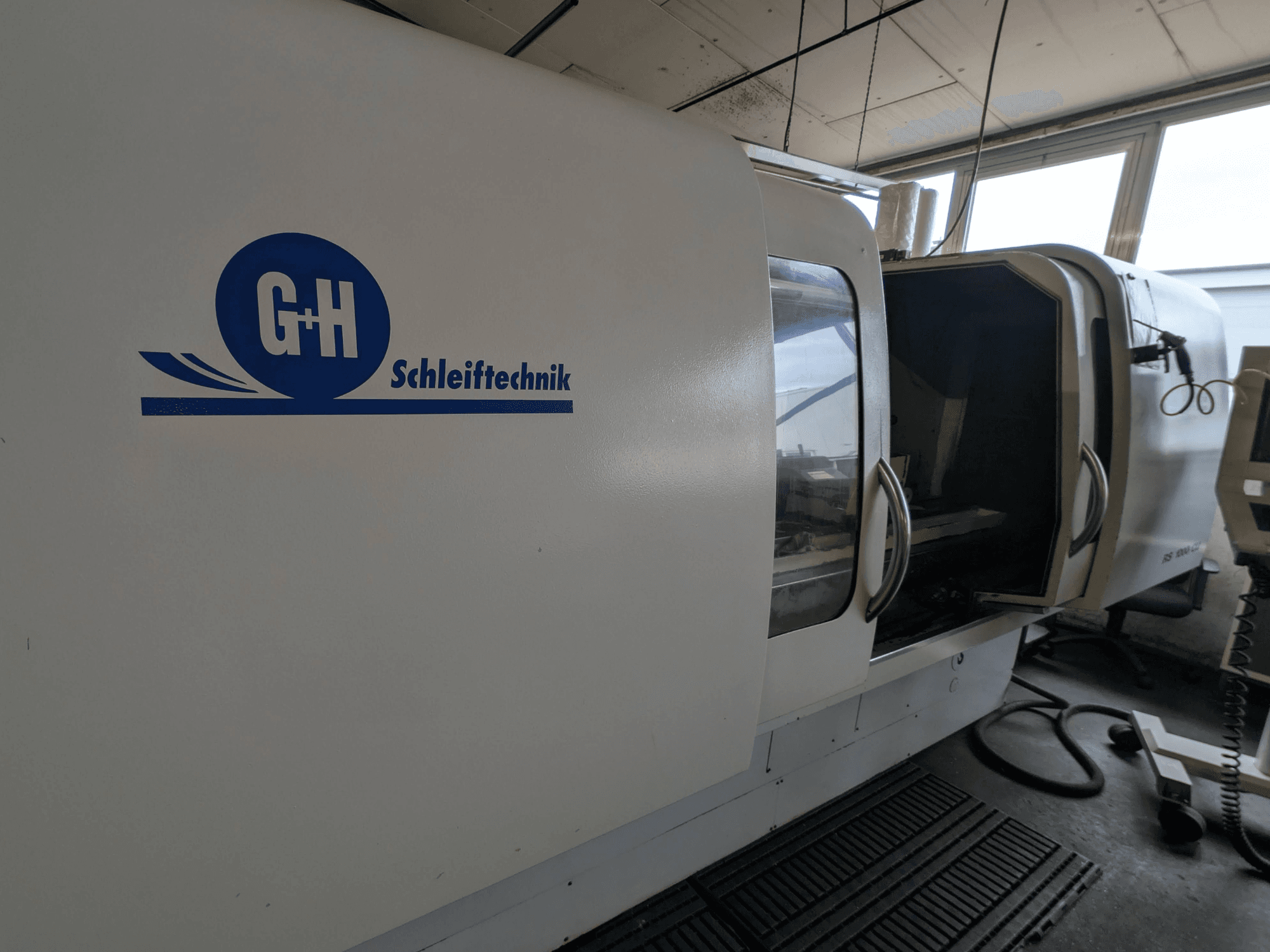 Rectificadora cilíndrica GEIBEL & HOTZ RS 1000 CU, vista lateral mostrando o painel de controlo e a porta de acesso aberta.