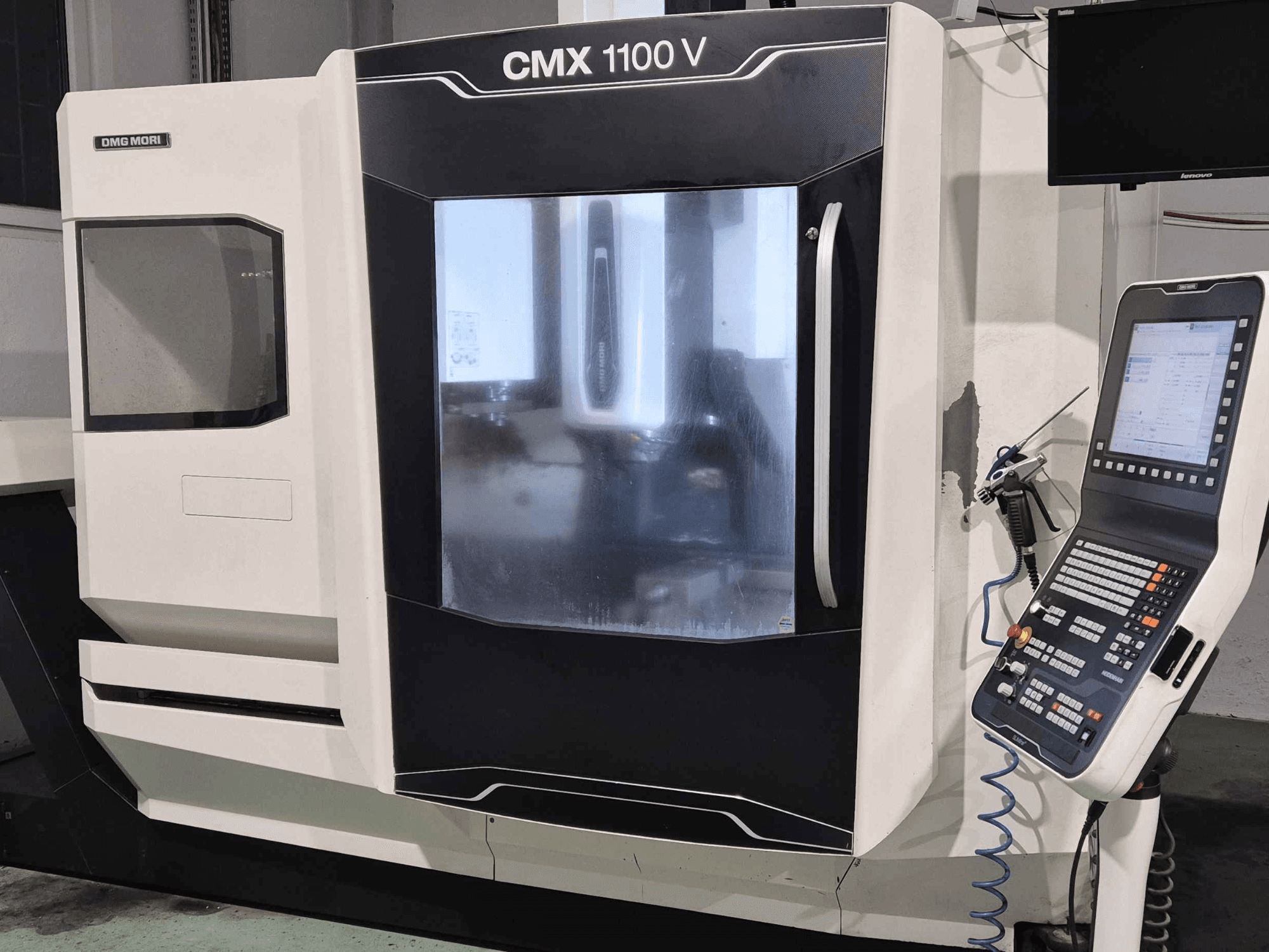 DMG Mori CMX 1100 V, vista frontal da máquina CNC com painel de controlo, visor digital e configuração do líquido de refrigeração visíveis.