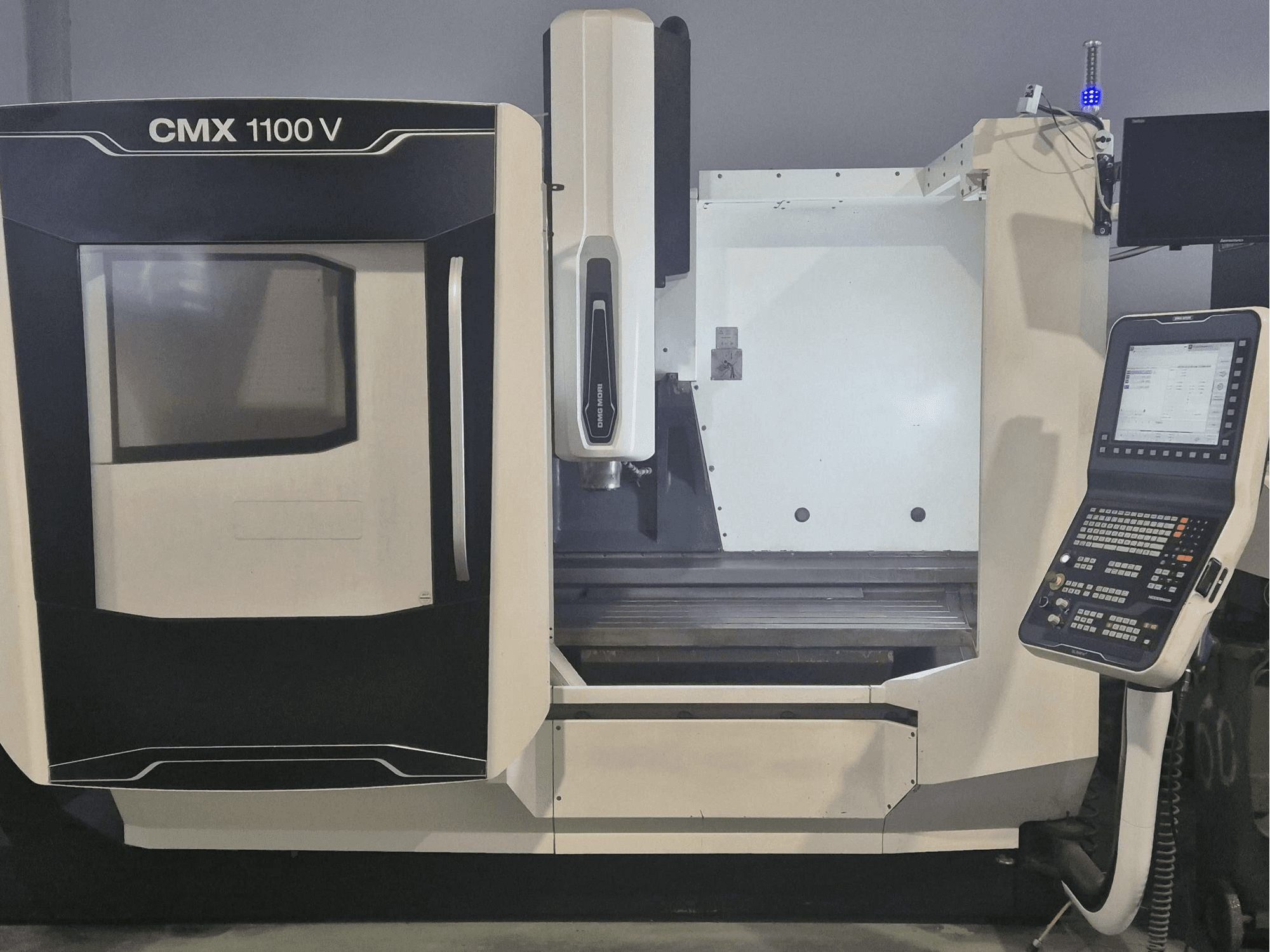 Centro de maquinagem vertical DMG MORI CMX 1100 V, vista frontal que mostra o painel de controlo e a base da máquina.