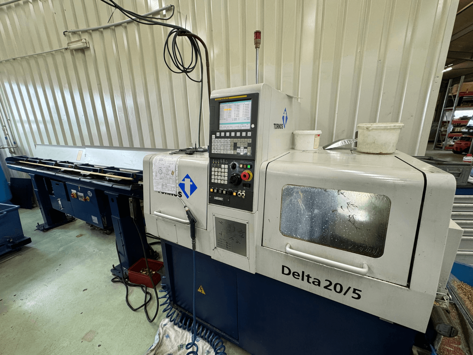 Máquina CNC Torino Delta 20/5, vista frontal, com painel de controlo e espaço de trabalho. Com vidro gravado e cablagem visível.