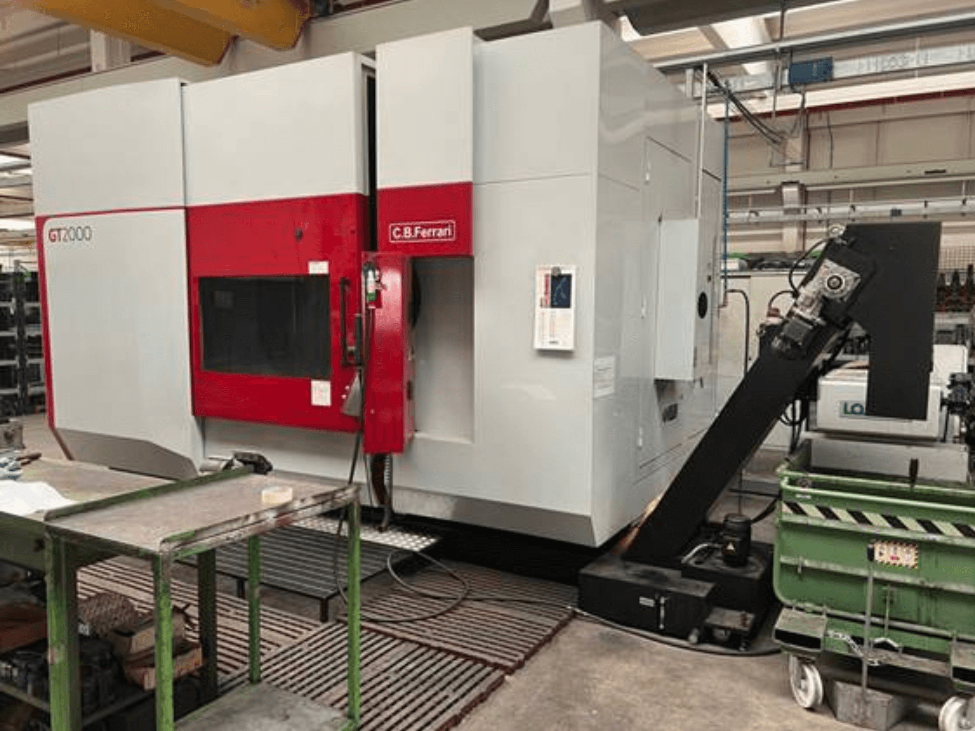 Fresadora C.B. Ferrari GT2000 em vista frontal, com braço robótico e espaço de trabalho industrial com carrinho verde.