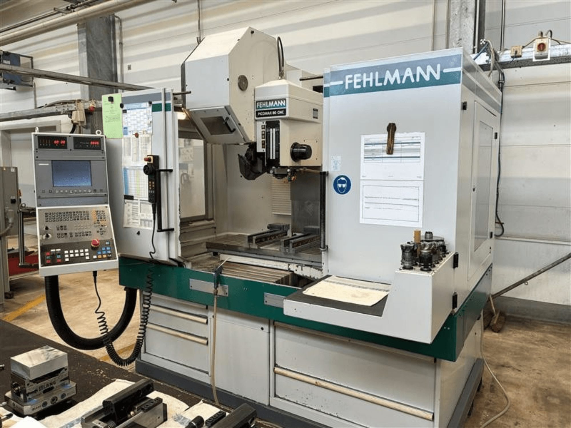 Centro de maquinagem vertical FEHLMANN PICOMAX 80 CNC-W 2/3, visto de frente, apresentando um painel de controlo e a área de trabalho de maquinagem.