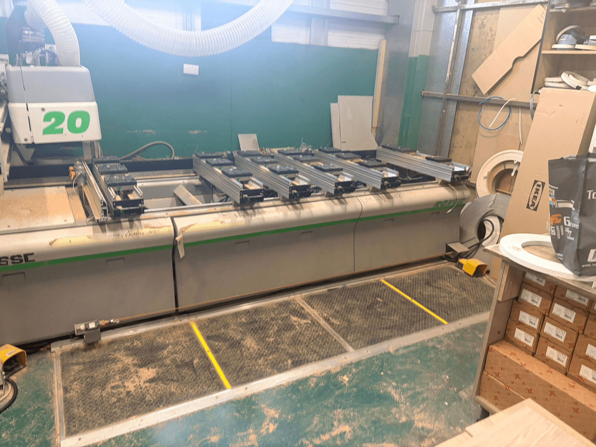 Centro de maquinação CNC para madeira BIESSE ROVER 20, vista frontal, com sistema de calhas, comandos e serradura visíveis na superfície.