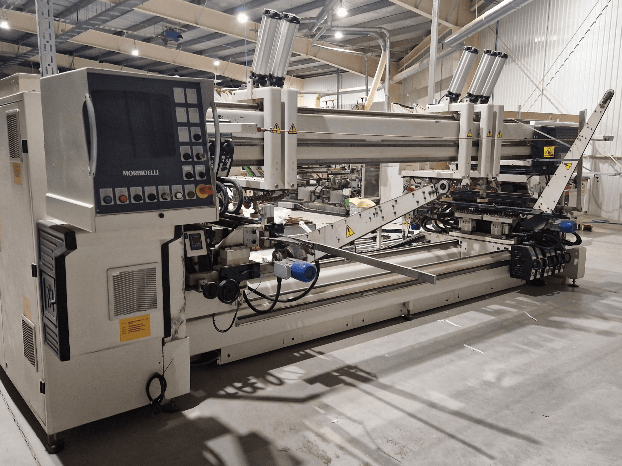 Máquina de furar multi-eixo SCM Morbidelli Zenith F2, vista lateral mostrando o painel de controlo e os componentes mecânicos numa oficina.