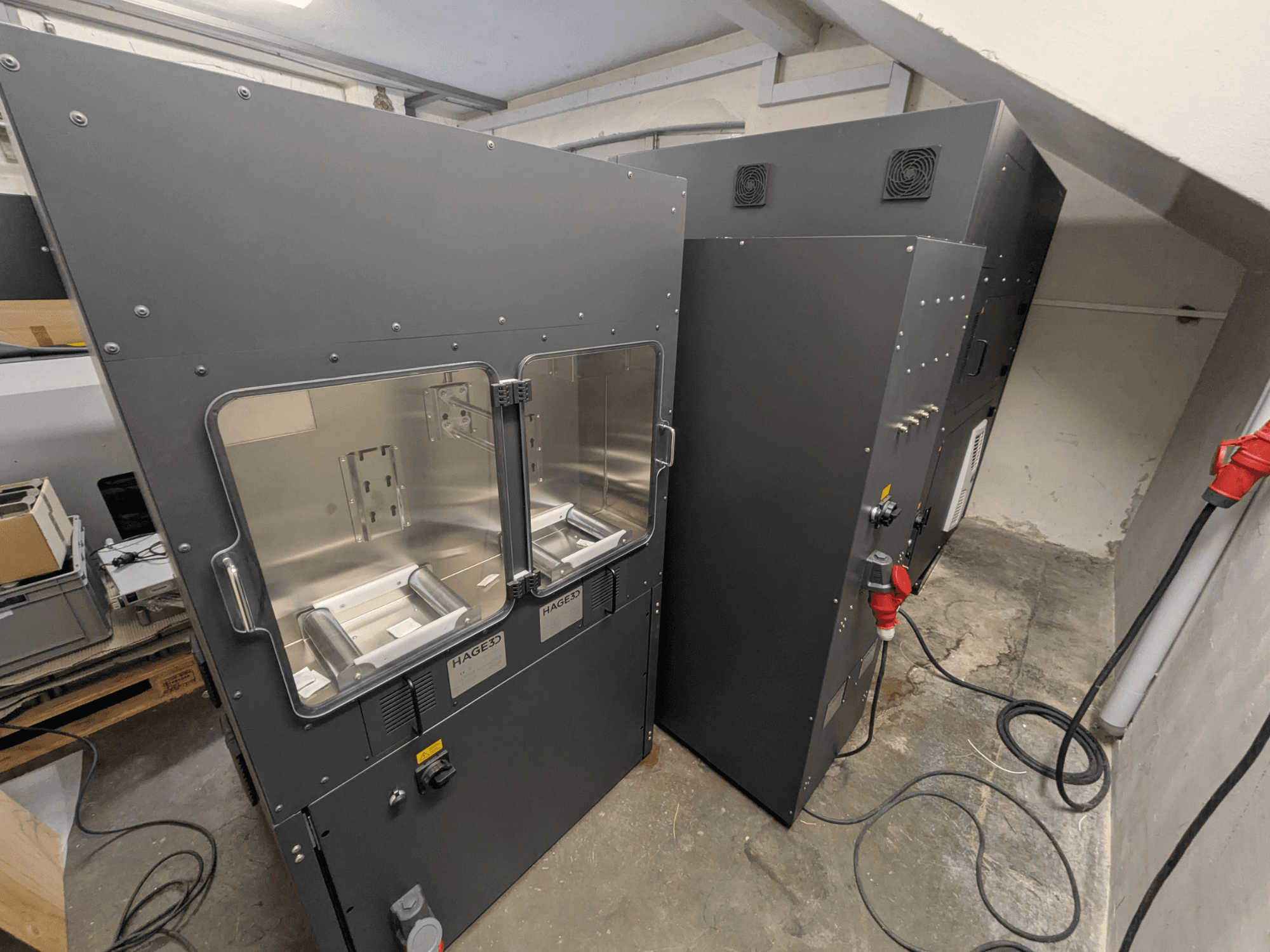 Impressora 3D de plástico HAGE 3D Mex-One-A, vista lateral que mostra as duas portas transparentes e o painel de controlo.