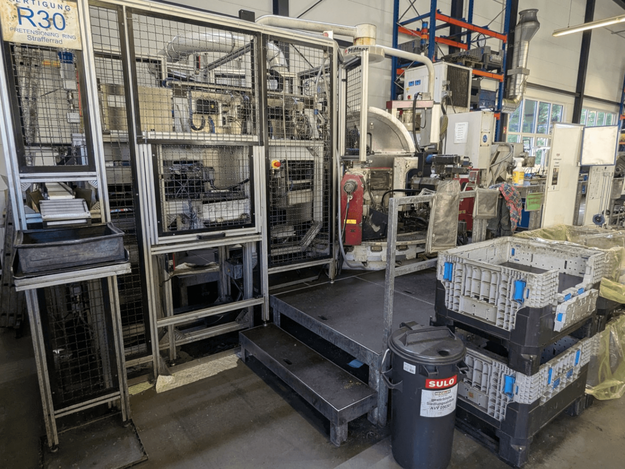 Máquina-ferramenta PFIFFNER HB 32/16 numa oficina, vista frontal que mostra a área de produção com caixas de armazenamento e vedação de segurança.