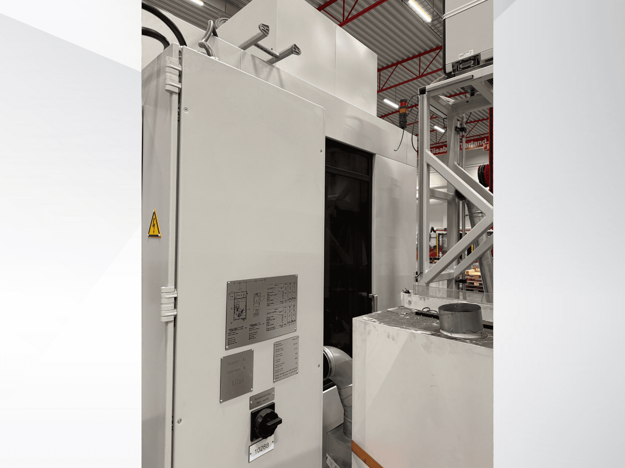 Vista lateral de uma máquina industrial branca com painel de controlo e etiqueta de aviso, parte de um sistema automatizado.