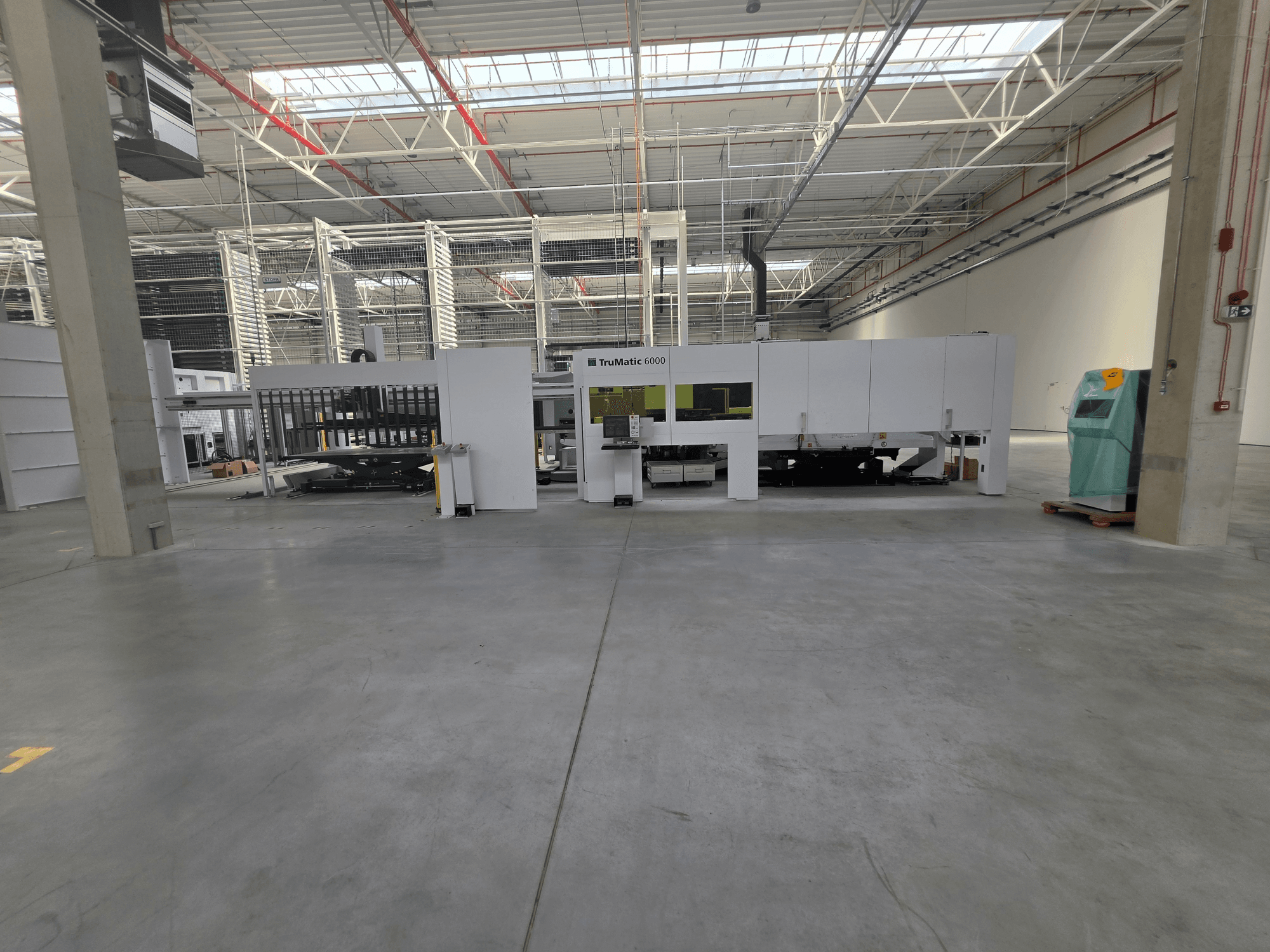 Máquina combinada de puncionamento e corte a laser de fibra TRUMPF TruMatic 6000-1600 num armazém espaçoso, vista de frente.