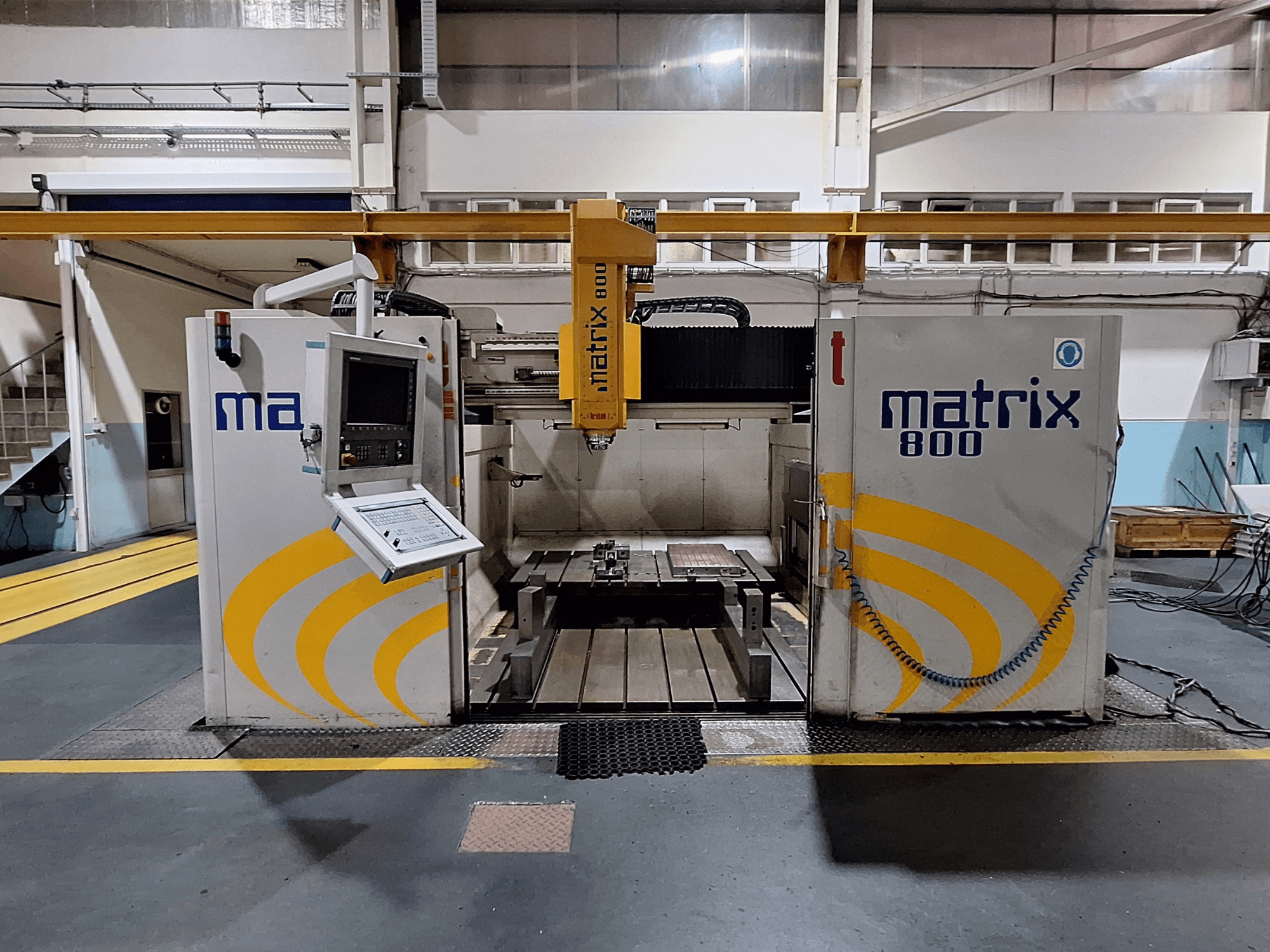 Fresadora de pórtico Breton Matrix WM 800 K25 numa oficina, mostrando o painel de controlo e a mesa de trabalho a partir da vista frontal.