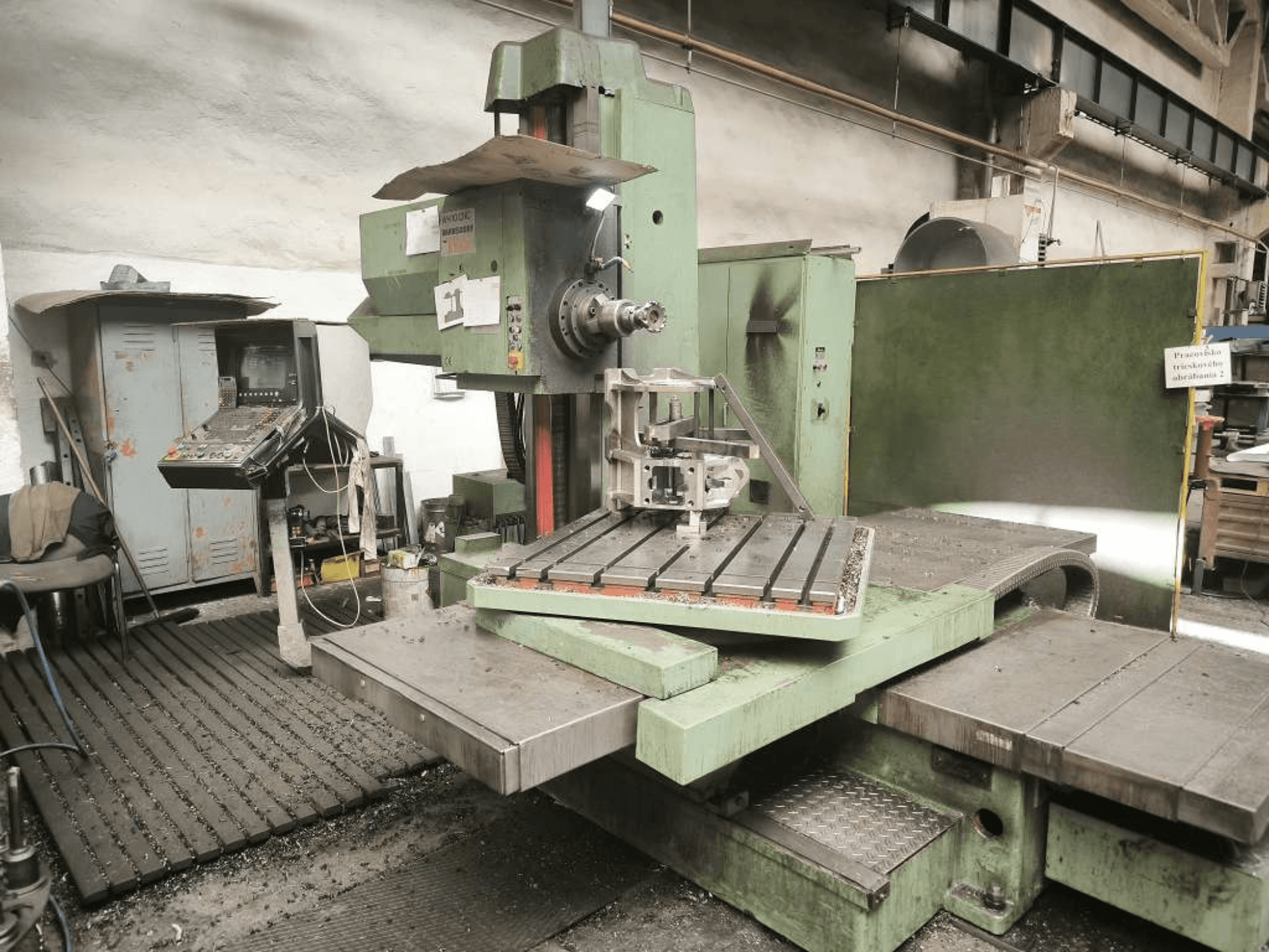 Máquina de mandrilagem CNC TOS WH 10 vista de frente, mostrando uma peça usinada na mesa e o painel de controlo.