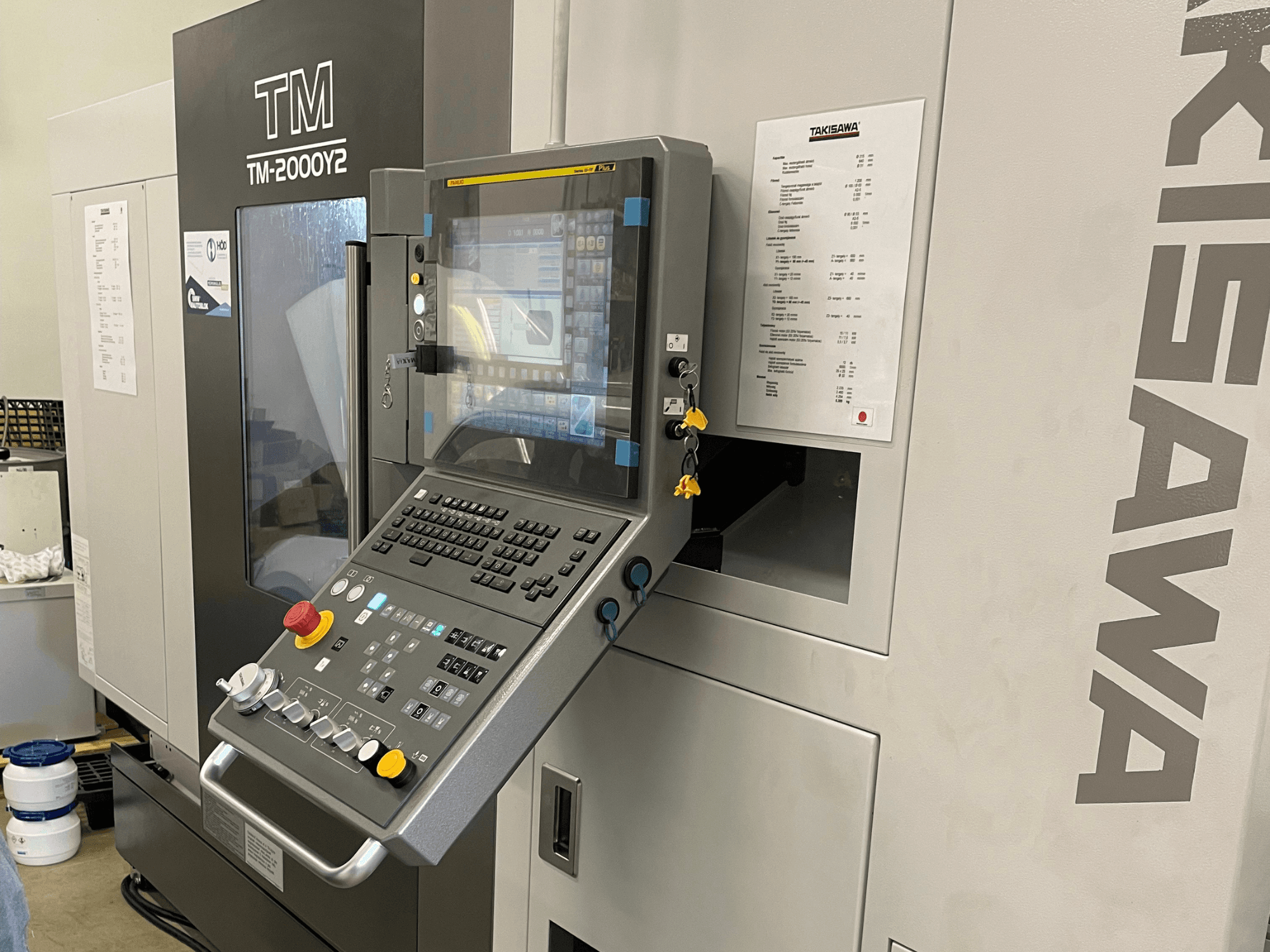 Painel de controlo do torneiro horizontal Takisawa TM-2000Y2 em vista frontal, com um visor digital e botões operacionais.