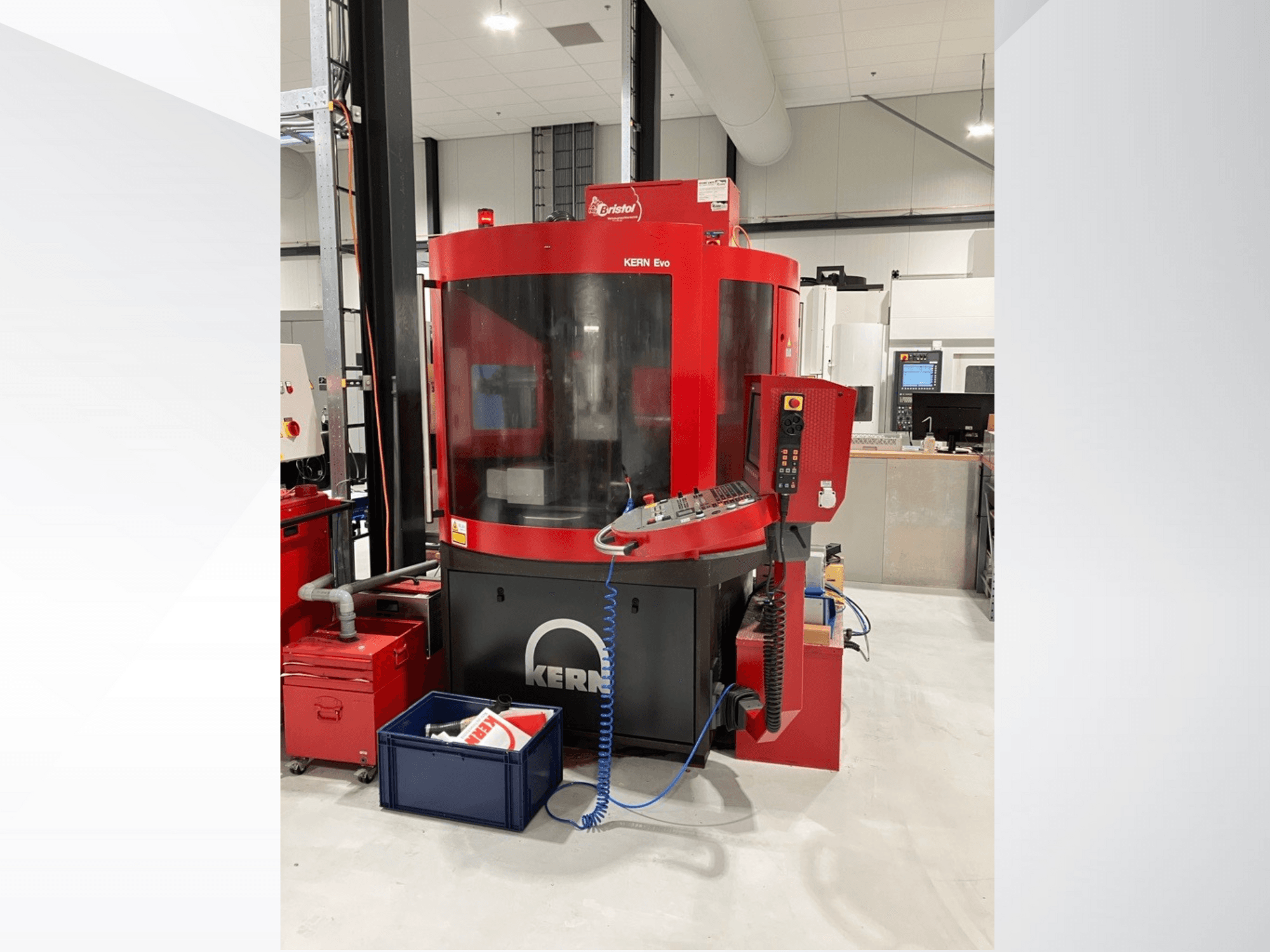 Centro de maquinação KERN Evo em vermelho e preto, vista frontal, mostrando o painel de controlo e o equipamento circundante numa oficina moderna.