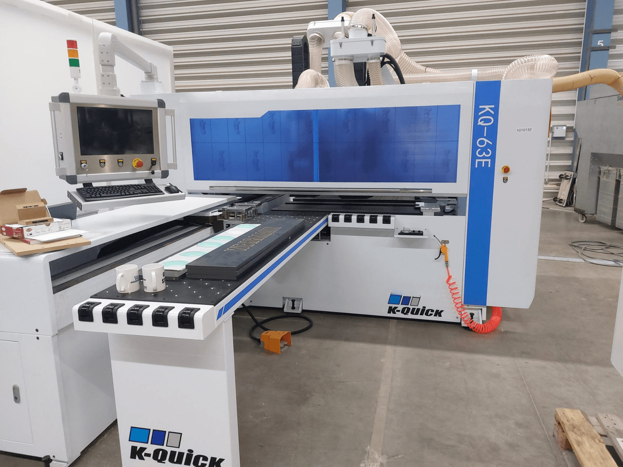 Máquina CNC K-Quick KQ-63E vista de frente, com um painel de controlo, mesa plana e colocação de ferramentas visível.