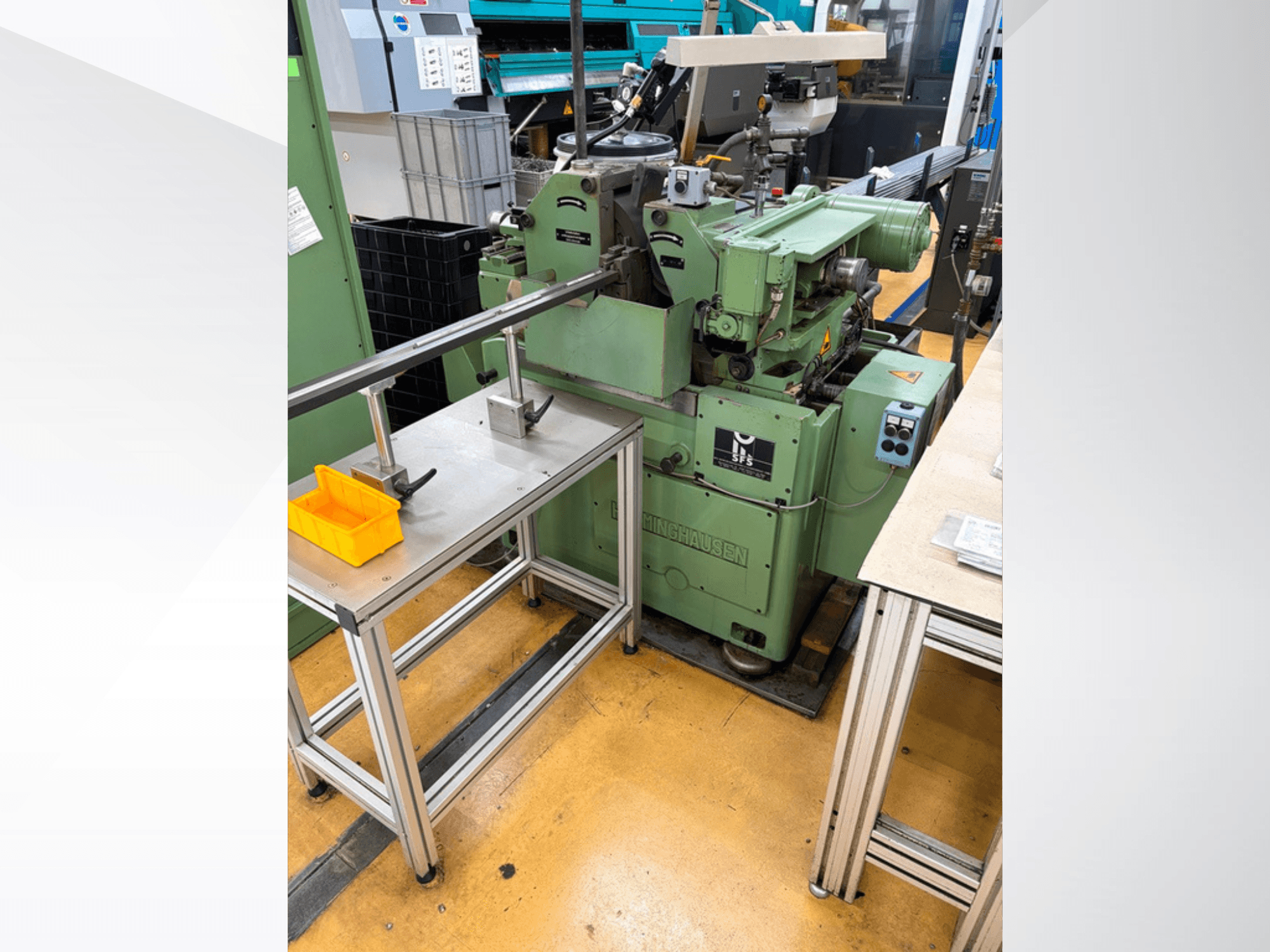 Máquina de retificação sem centros HERMINGHAUSEN SR 2 W, na cor verde, vista frontal, posicionada ao lado de uma bancada de metal com ferramentas.