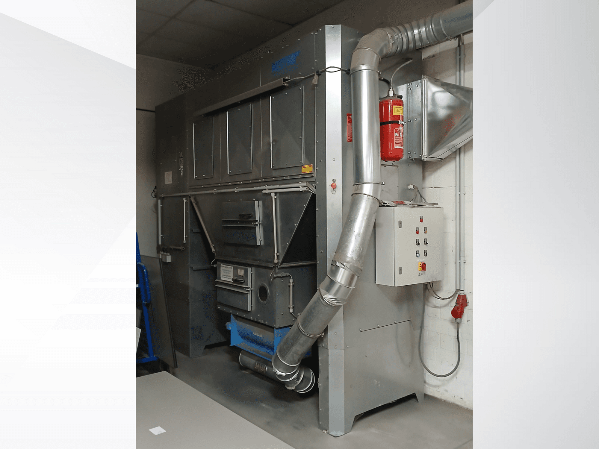 Unidade de recolha de poeiras industriais, metal cinzento, vista frontal; possui conduta de exaustão, painel de controlo e extintor de incêndio.