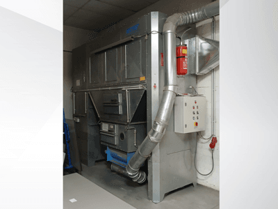 Unidade de recolha de poeiras industriais, metal cinzento, vista frontal; possui conduta de exaustão, painel de controlo e extintor de incêndio.